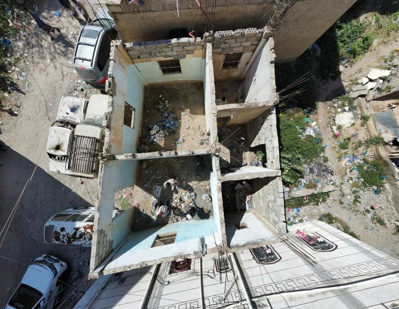 Aerial photo of a destroyed house. The walls are exposed, as the house no longer has a roof.