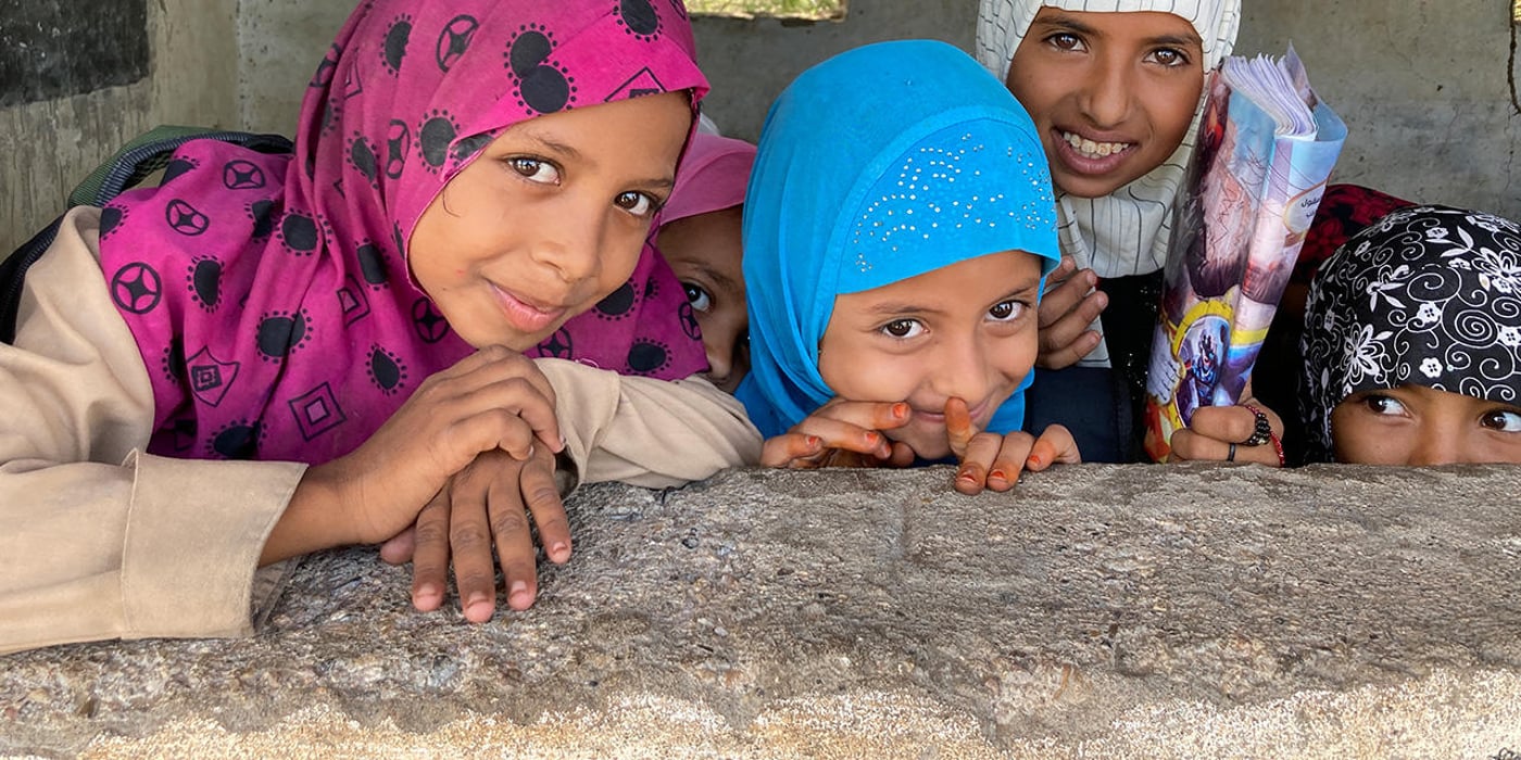 Five young girls looking over a concrete wall.