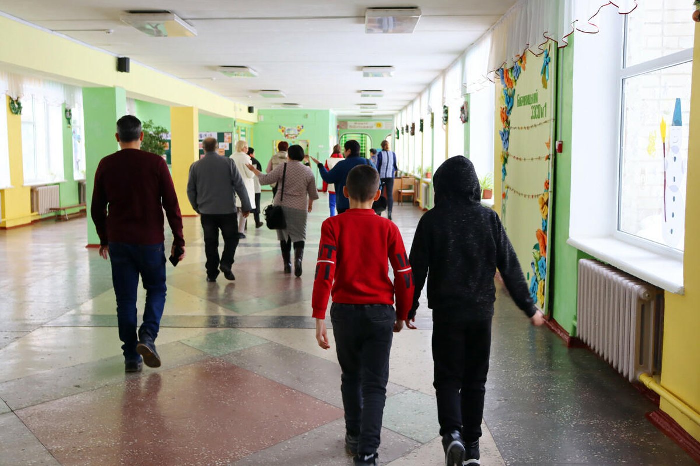 Students and staff members walking along a school hallway. 