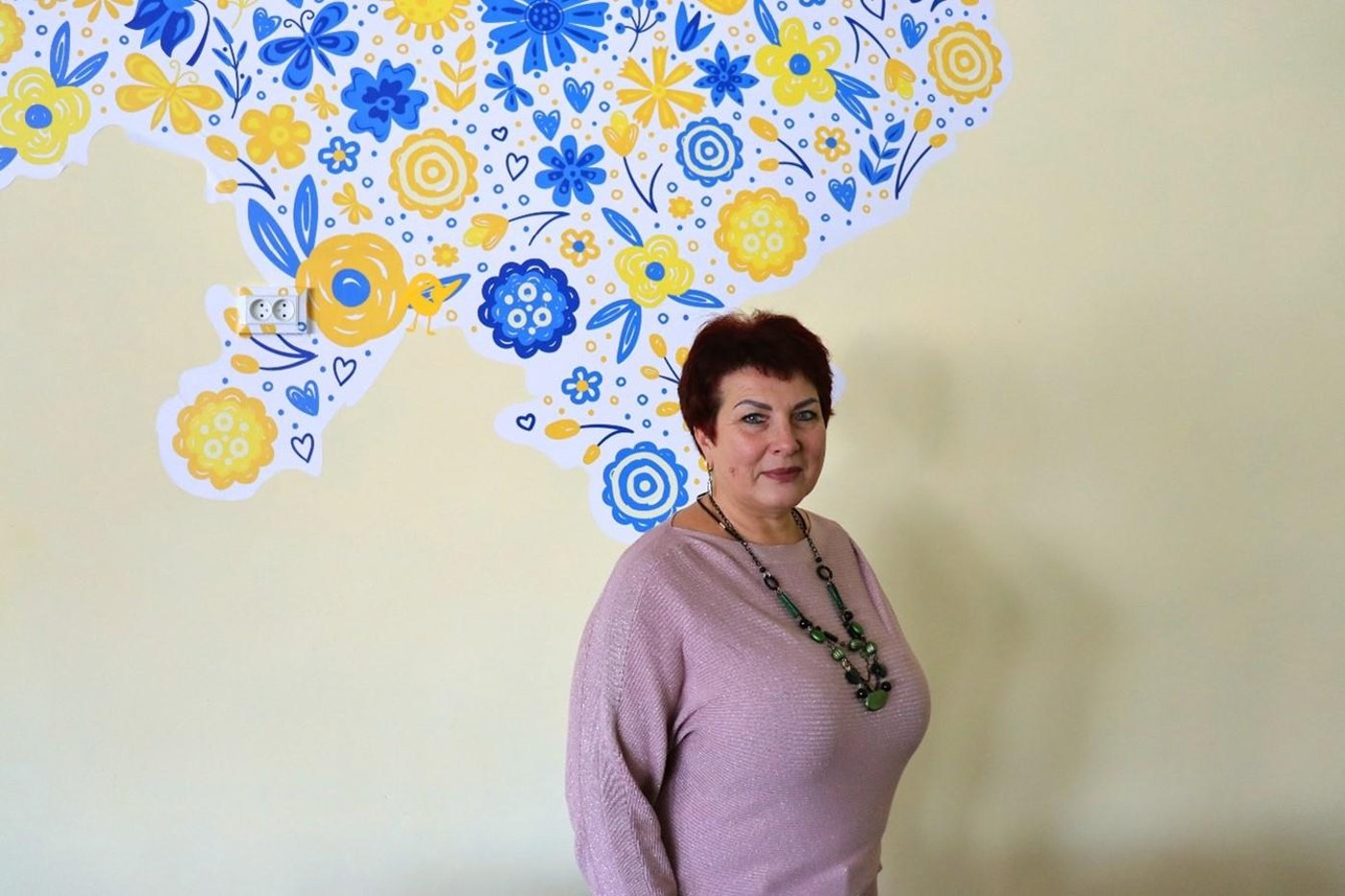 Vita Lysenko, director of the school in Bobrovytsia standing in front of a freshly painted map of the Ukraine in the assembly hall.