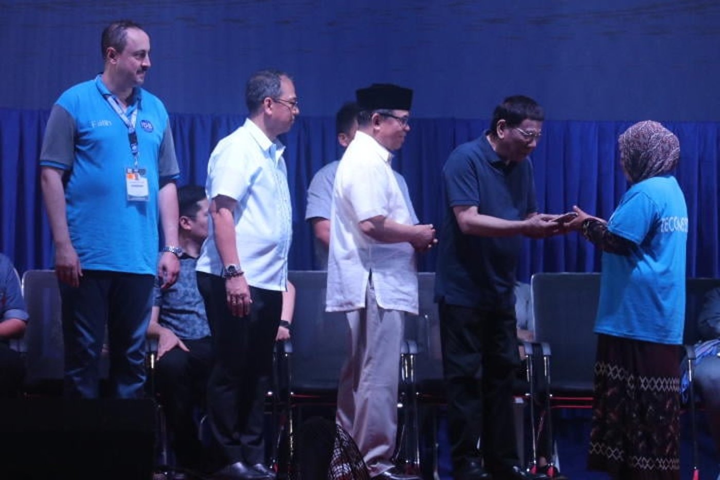 Philippines President Rodrigo Duterte shakes hands with a decommissioned M.I.L.F. combatant on stage at the ceremonial launch of the second phase of decommissioning