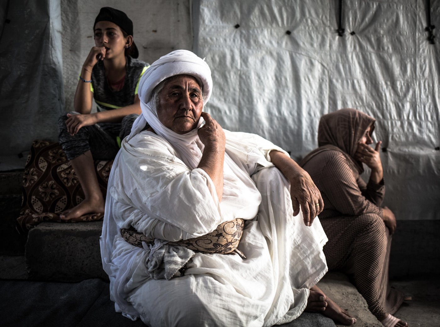Hundreds of thousands of Yazidis now live in displacement camps scattered across Iraq's northern Kurdistan region. In Bajid Kandela camp, white tents stand in long neat lanes, flanked by abandoned cars.
Base Khalaf, 60 years old, has been displaced with her family in this camp in Dohuk for 4 years now.
"Islamic State killed one of my sons four years ago. Since then I was unable to visit his grave. It is very hard to go back to Sinjar. The situation is not safe and the journey is very long," she says.
"Our life in the camp is difficult. There is little water and electricity. The tents are dirty, made of nylon, and easy to burn especially in the summertime. In the summer, many tents get burned and for an elderly and disabled person, it’s not easy to run. People have died because of this recently.
Winter is coming now and so is the rain, the cold and the wind. These tents will barely protect us. I wish I could go back home, but I just can't".
Photo: Tom Peyre-Costa/NRC
