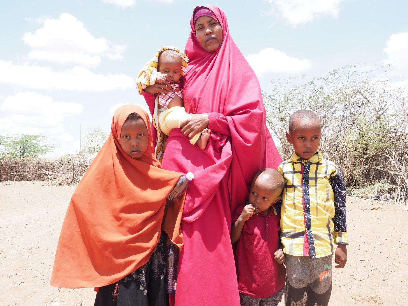 Halima Ahmed (24) and her children, Saadia (orange), Shueb (red) Mohamed (yellow) and 18-month-old son Mascud outside their home in Hagadera camp, Dadaab Refugee Complex, Kenya. Halima is planning to repatriate to Somalia with her four children and join her husband, who has already moved back to their country of origin after almost 10 years living as refugees.