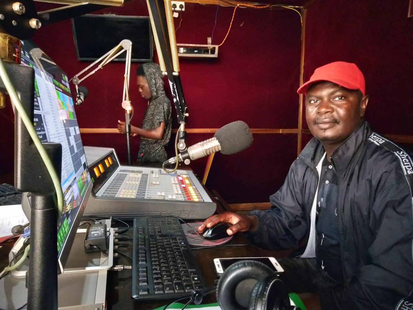 A man sitting in front of a microphone at a community radio station studio in the Sembabule District in Uganda.