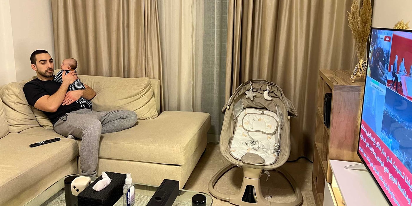 A father and his baby, watching the news at home