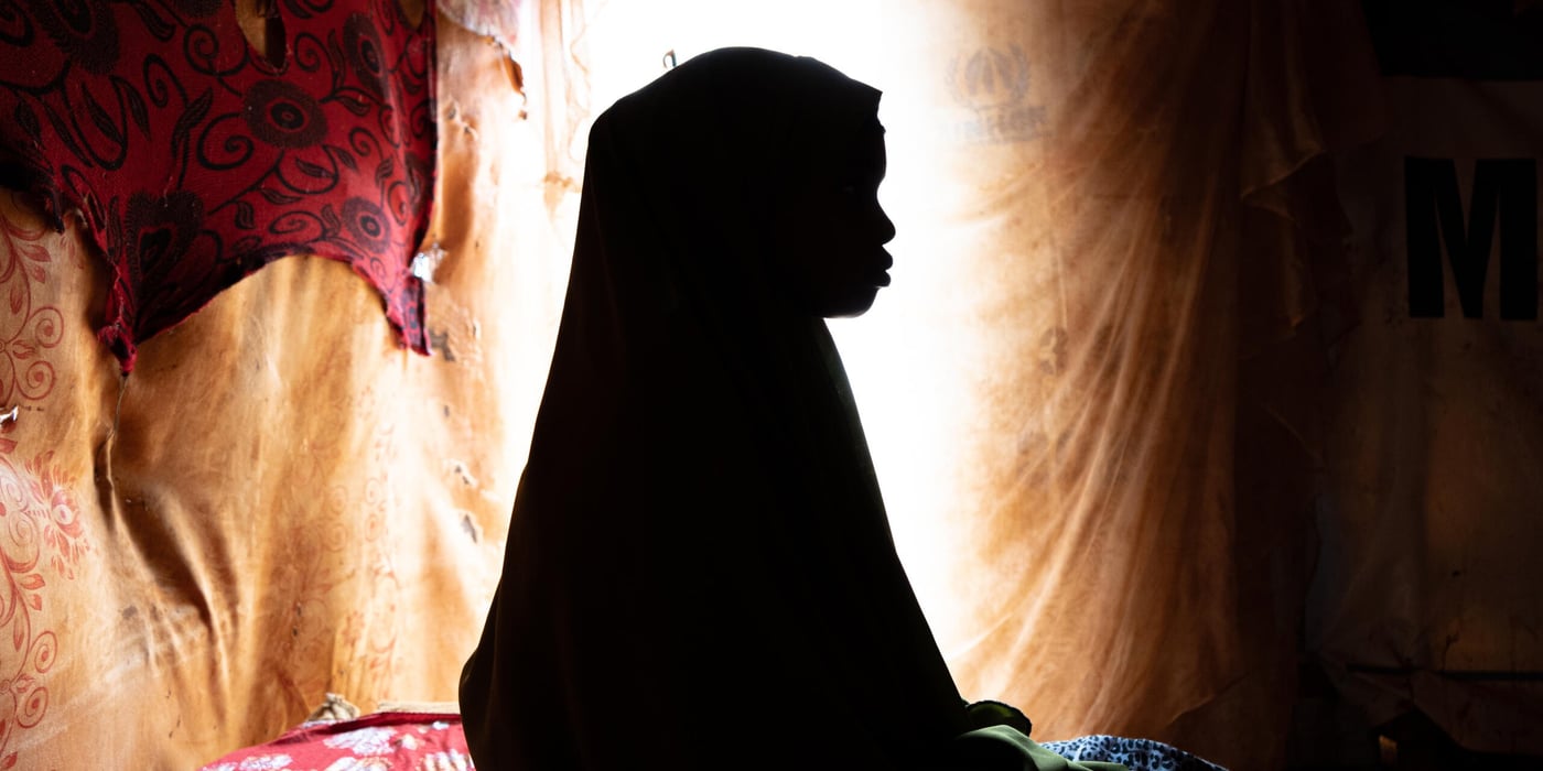 Flicka sitter i mörkret. 