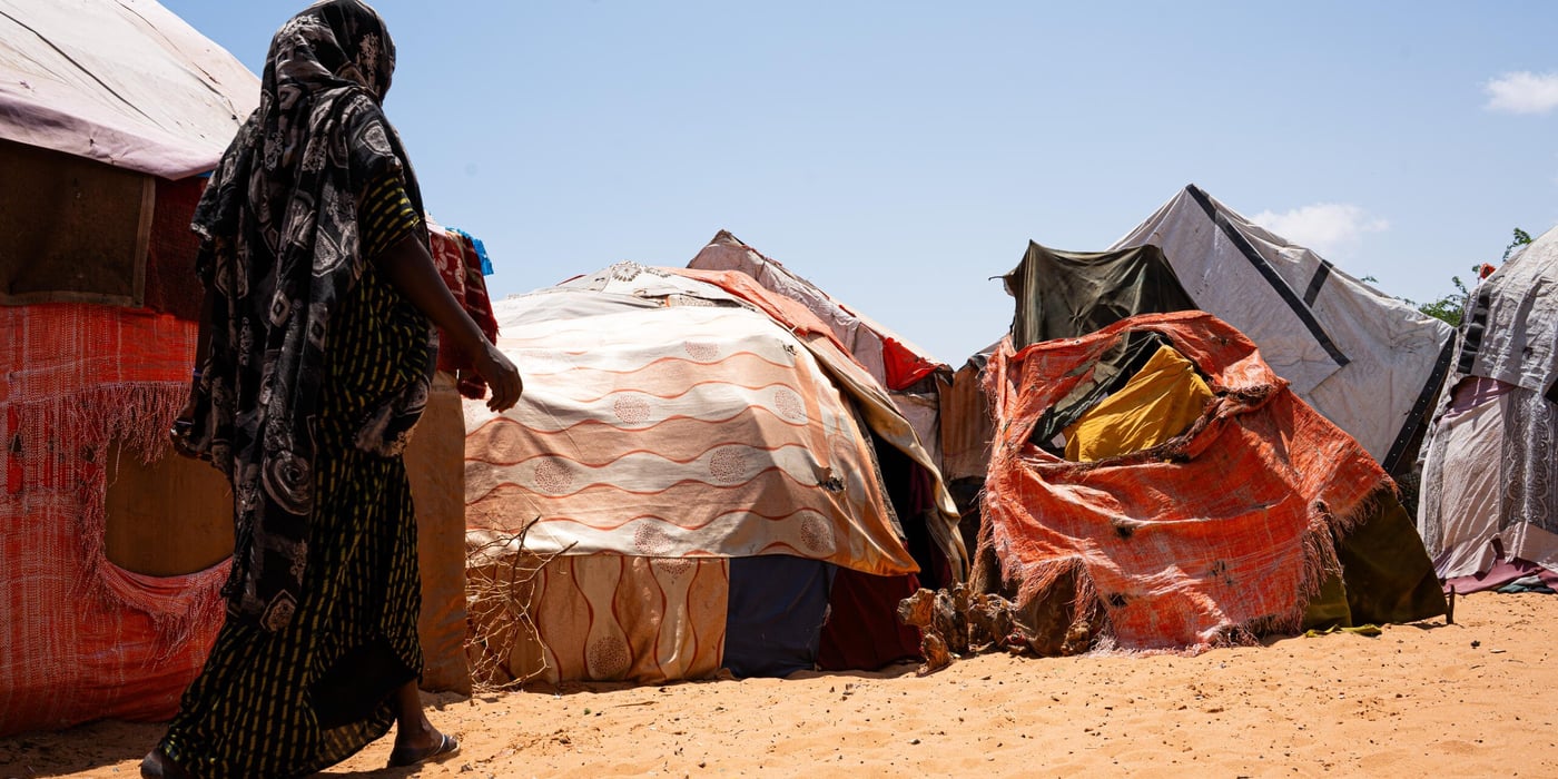 En kvinna går mot sitt tillfälliga skydd i Kahda-lägret i Mogadishu efter att ha flytt torkan i Lower Shabelle, där hennes hem och försörjning har gått förlorade.
