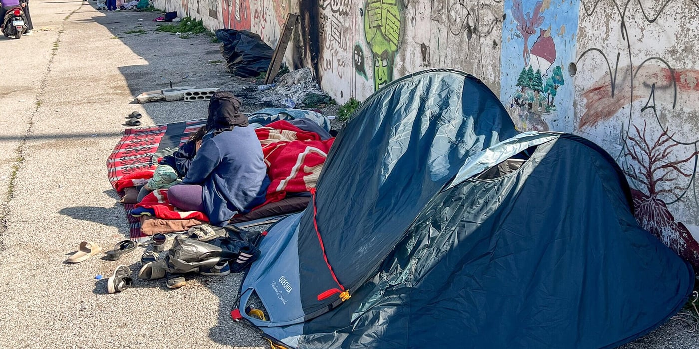 Fördrivna familjer sitter och vilar bredvid sina tillhörigheter utanför små tält längs en gata i Beirut.