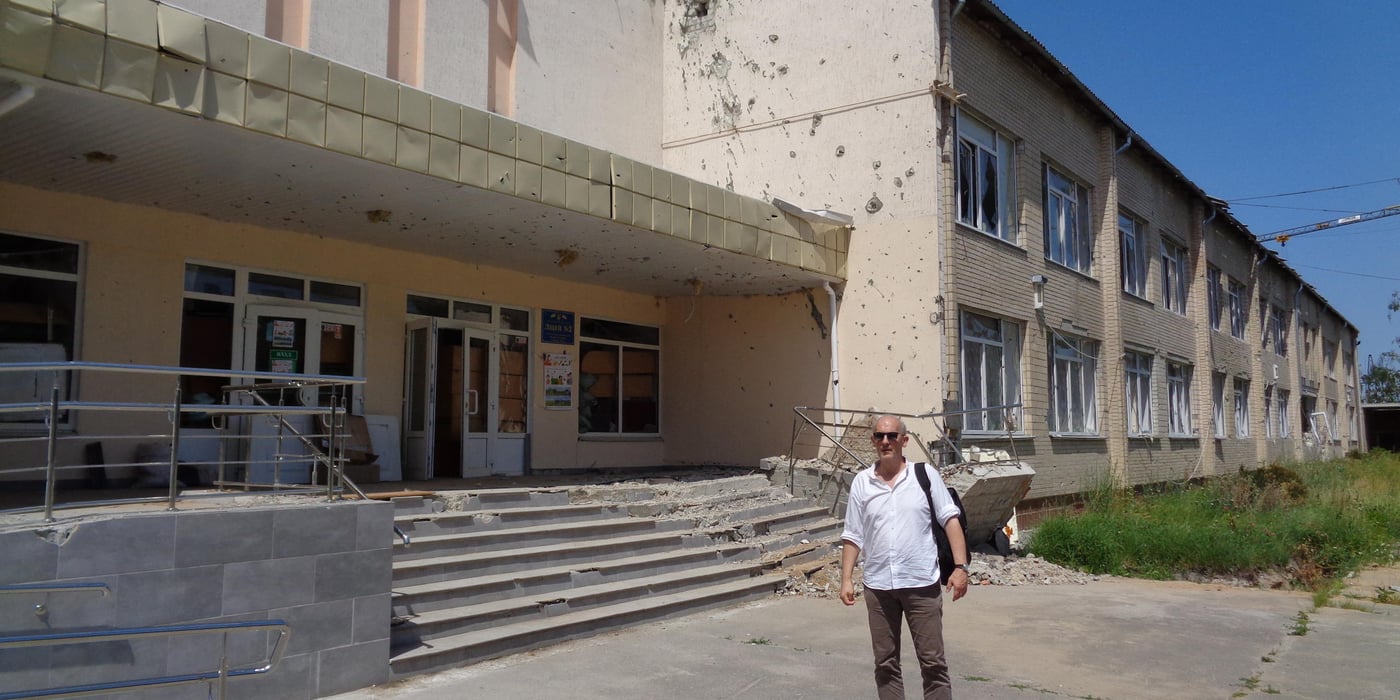 A man standing outside a damaged school.