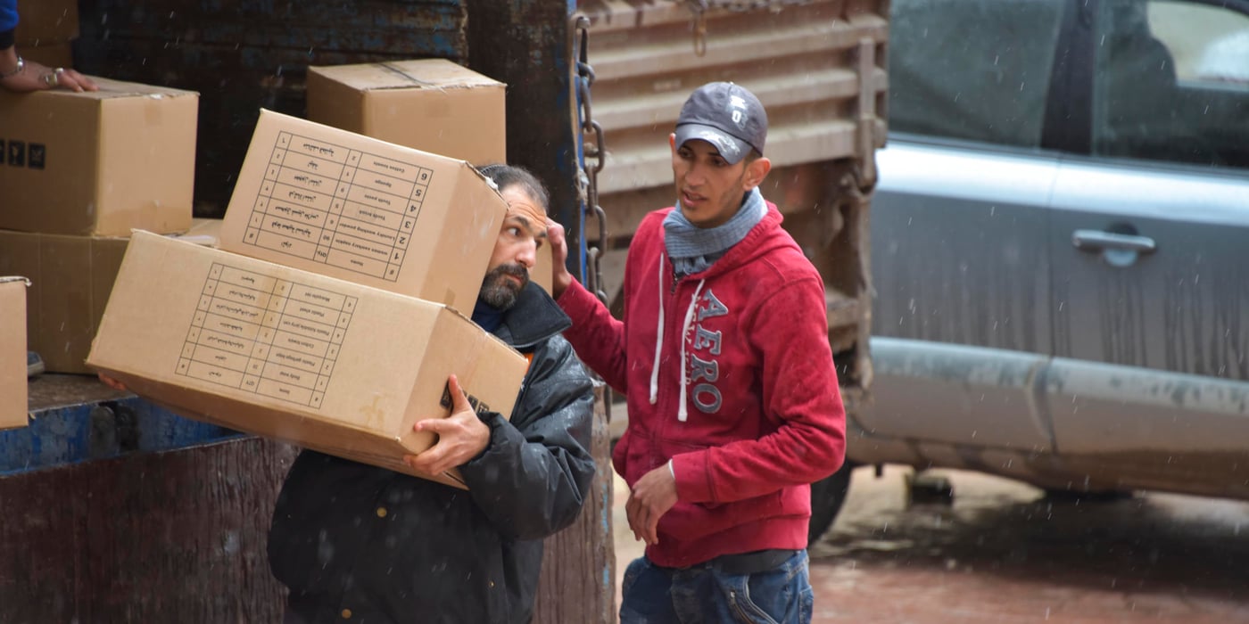 NRC staff offload relief kits from delivery trucks to distribute to families in Hazzeh, Eastern Ghouta. These boxes contain the necessities for everyday use (soap, hygiene items, blankets, mattresses, mats, jerry cans, plastic sheets and a plastic washing basin).
Photo: Tareq Mnadili/NRC