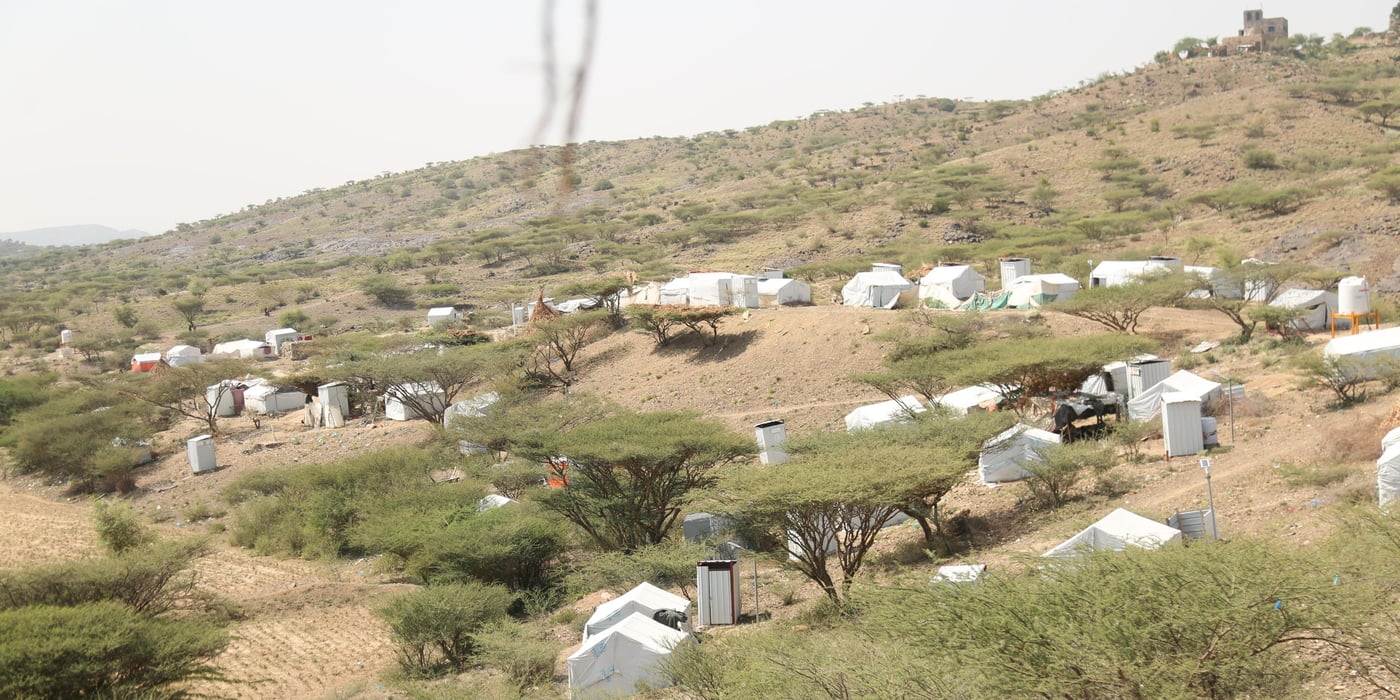 Landscape shot of Al-Rahabah camp. Tents are scattered in between trees and shrubbery.