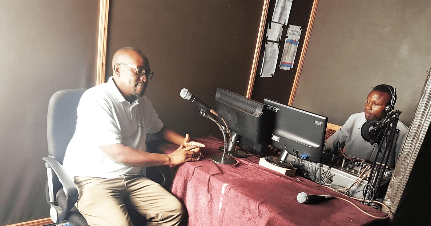 Two men sitting in a rural radio studio in Kenya.