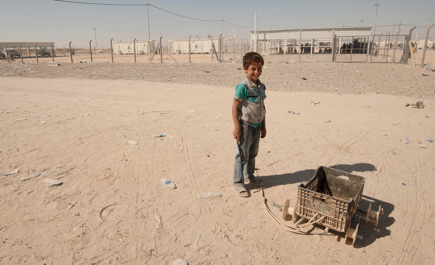 A young boy waits with a small cart to help people who have received aid carry it back to their tents in Kilo 18 displacement camp,
Since the beginning of October, hundreds of people have fled the town of Al-Qa'im in the Anbar province of Iraq in anticipation of a major military offensive to retake the are from ISIS. Many of these people have arrived in Kilo 18, a displacement camp near the town of Ramadi where NRC is providing them with immediate aid to meet their basic needs. Melany Markham/NRC October 2017