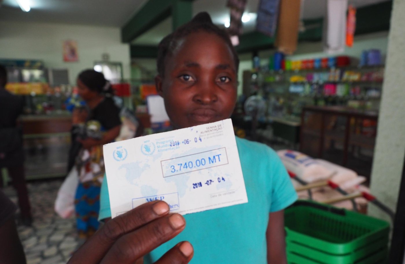 Young woman from Mozambique holding up a food voucher from the World Food Programme. (Photo: NORCAP/Ida Sem Fossvik)