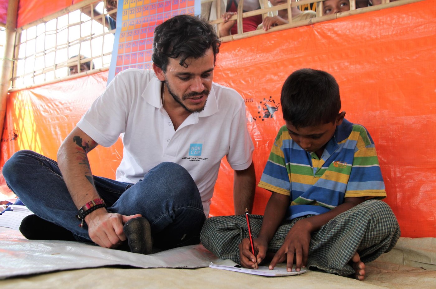 Education in emergencies expert, Henry Renna Gallano, with pupil Muhammed Imran (6). Muhammed attends classes in one of the UNICEF learning centres in Kutupalong camp in Cox's Bazar. (Photo: Ingrid Prestetun/NRC)