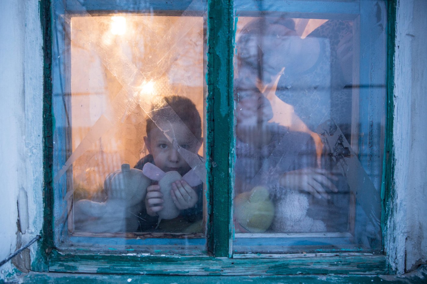Illia, 5 years old, is looking out of the window, with Iryna and Yana by his side. One February night back in 2015 his mother Liliia saved his life when shelling destroyed their house.
Background story:
Liliia Poturoieva is 39. She has experienced terrible events that completely changed the life of herself and her large family and left an indelible mark on everyone's soul. She lives in the frontline village of Verkhnia Vilkhova in Stanytsia Luhanska district, Luhansk region.
Liliia has six children. The oldest is Oleksandr. He is 20. He lives separately from his parents and earns his own living. Ihor is 12. He is a shy and calm schoolboy, always ready to help parents with the housework. Her eldest daughter Iryna is 10. She is a schoolgirl and mother's main housekeeper. She cooks and looks after younger children. Yana is 7. She is a first-grade pupil. She is a cheerful, active and very energetic girl. The children are forced to go to school in a neighboring village 5 kilometers away, since there is simply no school in their village.
Her youngest son Illia,5, and daughter Aryna, 2, are always staying at home with their mother. The family cannot afford a kindergarten for children. Now Liliia is pregnant again. This will be the seventh child in the family. Her husband Viktor helps her to cope with all of them.
Before the conflict, the whole big family lived in a small house with two rooms. There was no work. The main income was child allowances and random earnings from the cows, goats, rabbits and poultry.
“There was no work in the village. There was no opportunity to travel to other settlements to work. We tried to make money by selling milk”.
In February 2015, at midnight, heavy shelling began. Viktor, Liliia's husband, went out into the yard to see the direction of the shots. Suddenly a shell fell near their yard, and the second shell landed 7 meters away from Viktor, who was standing on the house porch. Viktor got a serious shell shock and lost his hearing for a while.
The blast wave knocked out all the windows in the house. Under one of the windows there was a child's bed, where Liliia’s youngest son slept. That night Liliia saved the life of her son with her son.
“When the blast hit, I covered my baby with my own body, and the glass from the broken window hit me in the back”.
The consequences of that shelling are still noticeable. Liliia has problems with her speech. She is stuttering. She is not the only one.
“The children experience anxiety, concentration problems, fears and, as a result, urinary incontinence”.
The house was seriously damaged in the blast. All the windows were broken, the front walls were destroyed and the roof and the foundation were seriously damaged. However, Liliia and her family did not dare to leave because it was too risky to leave the house unattended. They tried to repair the house on their own. They covered the broken windows with plastic wrap. They even had to spend their nights in the basement because it was the warmest and the safest place in their household.There was no help from the local authorities.
“At first I didn’t want to ask for help. I did not believe that anyone would really help us. My husband advised me to go to the NRC office and find out about the Heavy repair project, because he heard that NRC had already helped someone in the village”.
Now the house is in the process of restoration. There is a new slate on the roof. Renovation works on the walls have been completed. Three small rooms for the children have been completed. New windows have been installed and internal works are being carried out now.
“The main thing for me now is that the active phase of the war does not break out again. I am afraid that my house will be destroyed again. After all, we hear the sounds of shots every night”, Liliia says.
Photo: Ingebjørg Kårstad/Norwegian Refugee Council