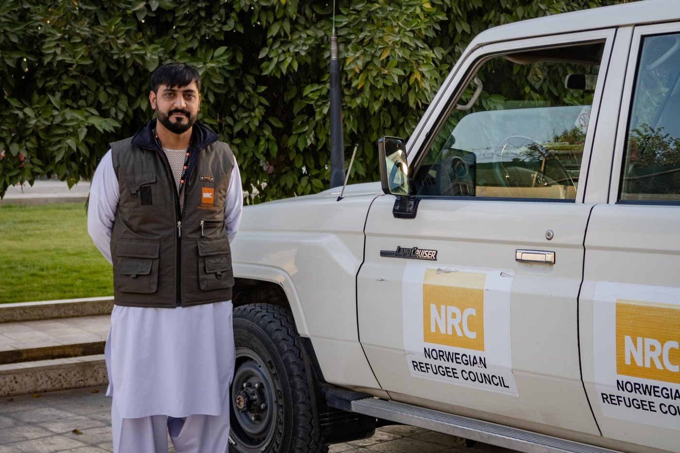 Noor Nawaz Shaiwani, wearing vest with the NRC logo, standing next to an NRC vehicle.