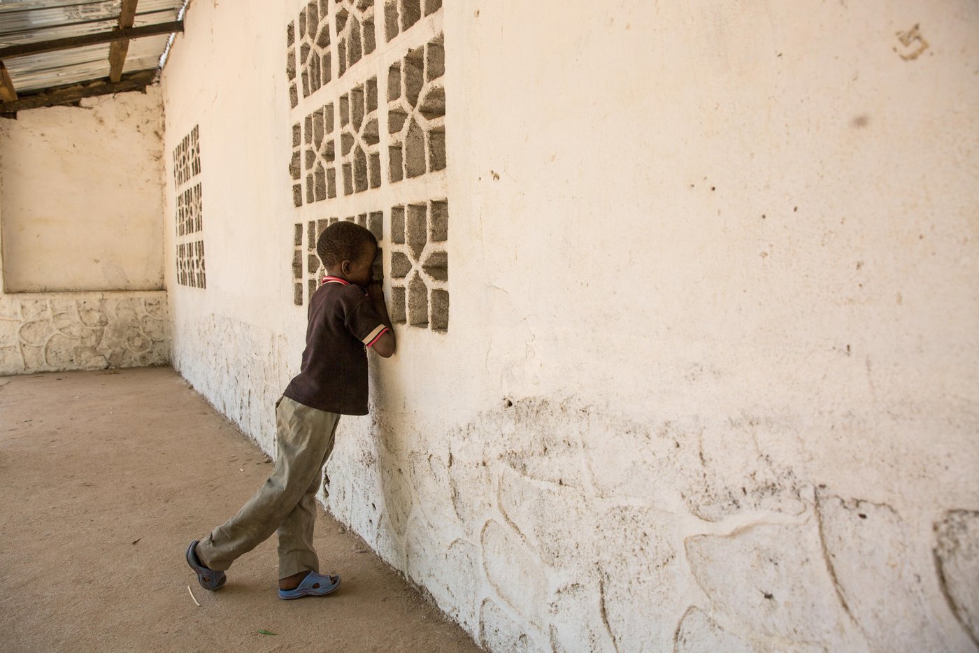 Boy, about 10 years old, looking in through a window. (Photo: Ingebjørg Kaarstad/NRC)