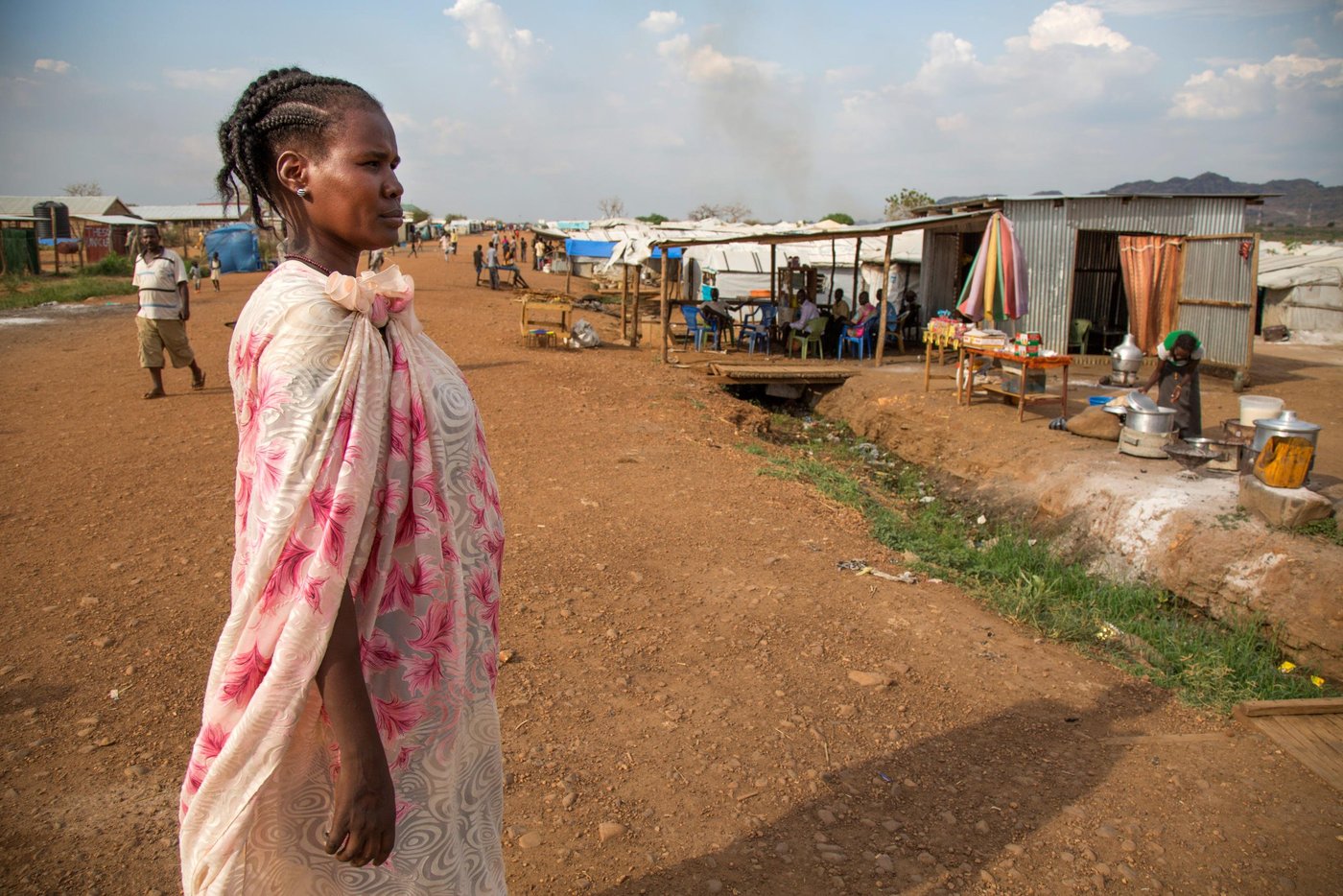 30 November 2016. Juba: Nyakuan Dador, originally from Mangatein, walks at the UN Protection of Civilians (PoC) site in Juba, South Sudan.
Nyakuan, mother of six children, doesn't know the whereabouts of her husband who is a member of the opposition forces. She has been displaced with her children since the civil war started nearly 3 years ago. The conflict officially broke out on December 15, 2013, between forces loyal to President Salva Kiir and those loyal to former Vice President Riek Machar. Since then, an estimated 1.6 million people has been displaced inside the new country's borders. In addition, more than 640,000 people have fled to neighbouring countries. Hunger is on the rise.
According to OCHA, more than 6.1 million South Sudanese are in need of protection and humanitarian assistance such as food, clean water, education and other basic services.
Nyakuan Dador's story:
Nyakuan moved to the PoC right after the conflict started in December 2013. Her husband goes regularly in and out of the IDP camp to work as a trader in different villages to help the family to move on. “But it’s really hard to sustain our big family with so little income,” she explains. That’s why she also runs a small restaurant at the PoC.
Nyakuan complains about the lack of good education and healthcare, and even food. “Life was very different before the war,” the woman remembers, “in our homeland we used to have money to pay the hospital and school fees.” The mother regrets they are totally under the assistance of the humanitarian organizations. “These organizations are our parents now,” she says.
Nyakuan is a real supporter of good education in the PoC. “If our children go to the school everyday, they will become something good in the future,” she believes. However, Nyakuan admits that teachers are not paid and school materials are very short. That’s why her only message to the international community is providing support on education for the new generations.
“It has been a long time since we celebrated a proper Christmas,” Nyakuan says. She would like to cook something special for her guests, “but now there is nothing to prepare and no guests to come to my shelter.”
----------------
Photo by Albert Gonzalez Farran - NRC