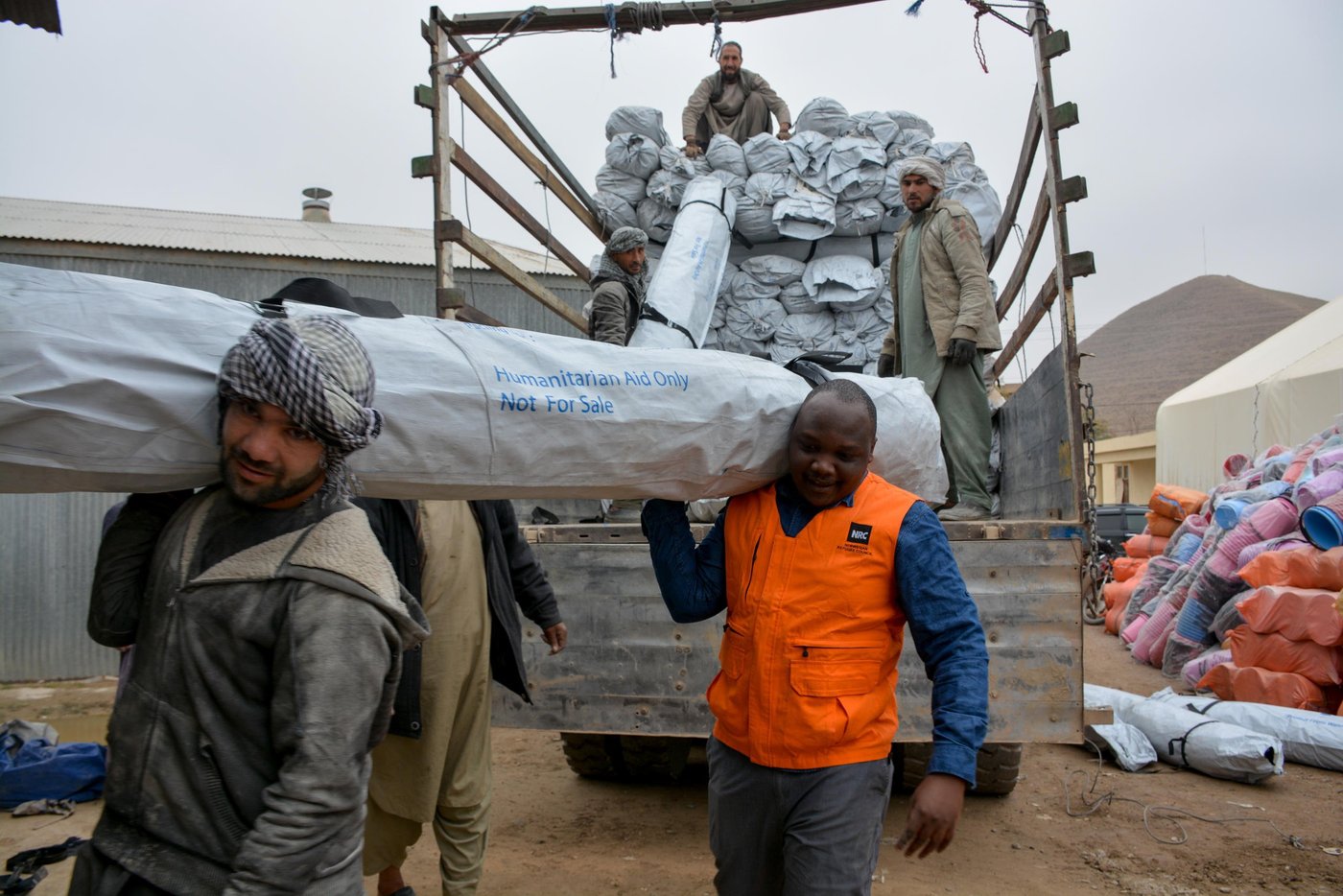 NRC team in Qala-i-naw assisting with unloading and hauling 735 tents for displaced families living in makeshift tents in Feristan IDP settlement in Badghis. The families have been displaced due recent drought and climate change and long lasting conflict in rural parts of Badghis. The tents are donated by ECHO. Photo: NRC/Enayatullah Azad