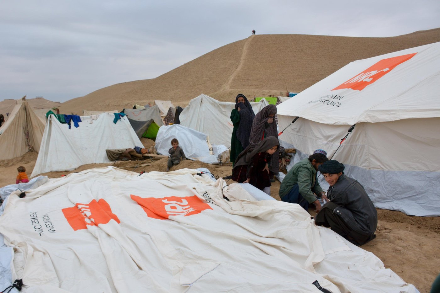 Families are erecting tents in Feristan IDP settlement donated by NRC with support from ECHO. The Family Tent has 16 m2 main floor area, plus two 3.5m2 vestibules, for a total area of 23 m2, double-fold with ground sheet to house an entire family of eight. This family tents have a life span of 1 year, minimum, maintaining its sheltering and waterproofing capacities in all types of climates.
Photo: NRC/Enayatullah Azad