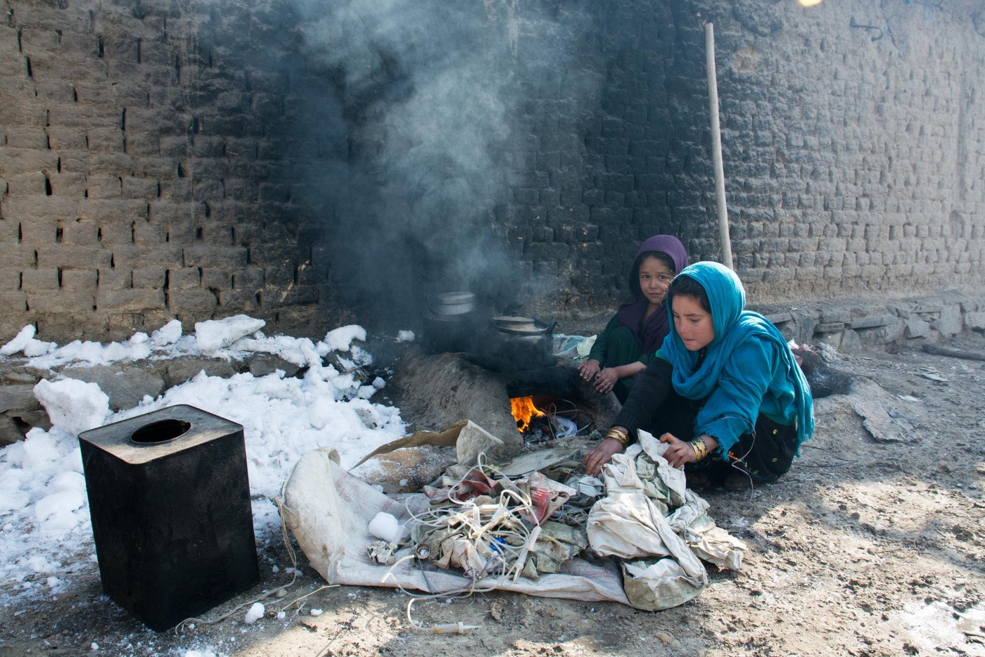 Haji Mohammad's grandchild Fereshta (in blue) boiling water burning waste plastics and papers. The family can't afford gas or firewood to prepare food.
Haji Mohammad, 80, has been forced to flee from Kunduz to Kabul. He and his 15 family members now live on a rented yard in the west part of Kabul city. He pays 2000AFN rent for a boundary with almost zero facilities. His sons and grandsons are all busy collecting scraps on the streets. They usually sell the cans and metals if the found and bring the papers and plastics home to cook food and warm up the room during the winter. Two of Mohammad’s children are disabled.
“when the USSR captured Kabul, my father took our family to Pakistan. When American’s came to Kabul, I took my children back to Afghanistan.”
“We went to Kunduz from Pakistan and began everything from the first steps. We do not have agricultural field in Kunduz so we started living as a Kochis/nomads with cattle like our forefathers used to live. Nothing was similar to what my father used to tell us. We had lost the pastures for our cattle and sheep.”
Then the fighting began and the finally government told us to leave the area if we want to safe our lives.” Photo: NRC/Enayatullah Azad