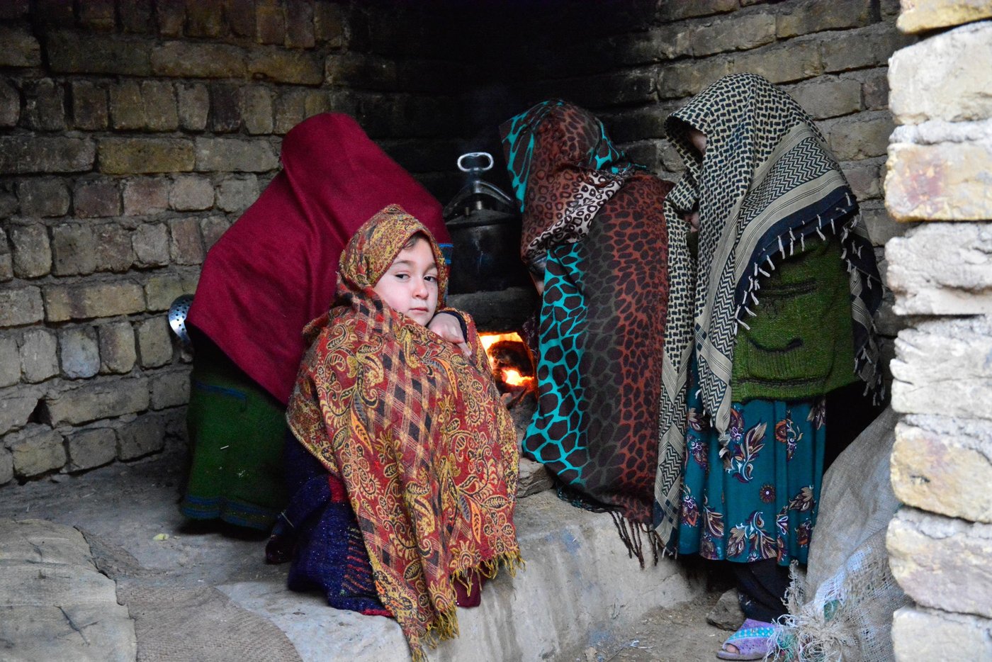 Adila (8) warming herself in the kitchen on chilly afternoon in Maimana city. Six months ago the school she used to go to in his home village in Almar district closed due to insecurity. Four days ago his family had to flee their home due to heavy fighting in the area. Now they are stuck on the outskirts of the provincial capital of Maimana without work, money or protection from the winter cold. After having assessed their situation, NRC will start providing assistance in coming days. Photo: NRC/Enayatullah Azad