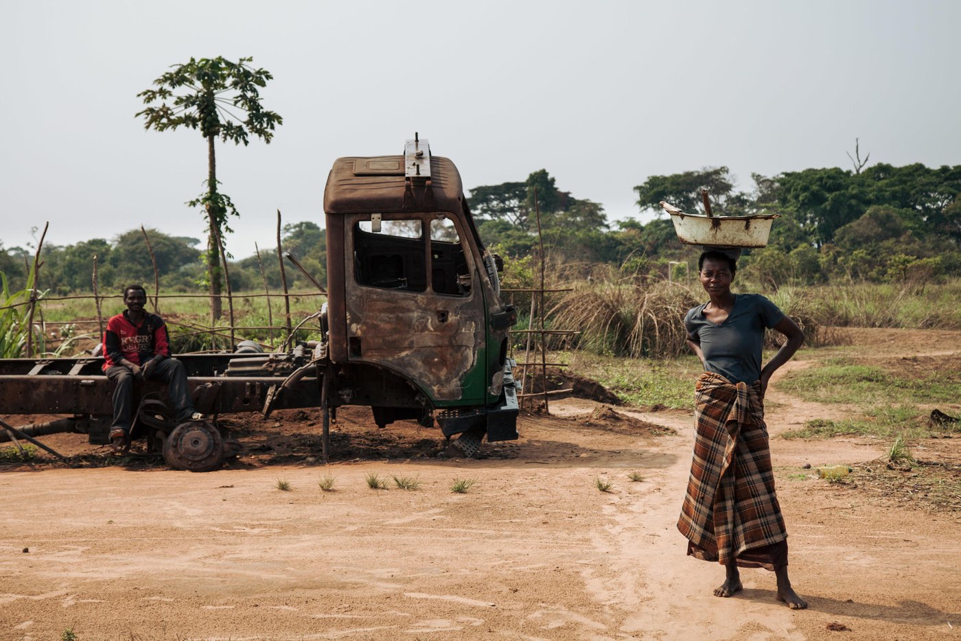 Sangamai Teka, 41, a farmer in Mbulungu village, poses beside a burnt-out truck that was destroyed when armed groups attacked the village in March 2017.   Sangamai is one of the 3,000 people who benefited from NRC's cash-for-shelter programme in the villages of Mbulungu and Bakuakashila, Kasai-Central.

Over 1 million people have returned to their homes in Kasai-Central after a year of violent conflict within the province and across the Greater Kasai Region.  Unfortunately, people who have returned have found their homes and fields pillaged and burned to the ground.  These farming communities have no shelter, no food to eat and no means of sustaining any viable livelihood.

Earlier this year, NRC visited Mbulungu and Bakuakashila, two villages ravaged by the regional conflict in 2017.  NRC used its “community-based approach” by consulting with these communities to better understand their primary needs, to properly target the most vulnerable people and facilitate their ability to choose the assistance they require.

This intervention, however, is only a drop in the ocean of the vast needs of this community.  NRC is currently the only humanitarian actor in the zone and funding is not enough to address other acute needs such as food assistance, household items and education.  The Humanitarian Response Plan is currently only 25 per cent funded eight months into the year.  Humanitarian capacity is critically low.  If donors do not act now for the people of Mbulungu and for the rest of DR Congo, it will be too late.

August 29, 2018- Kasai-Central Province, DR Congo
Photo : NRC/Aléxis Huguet