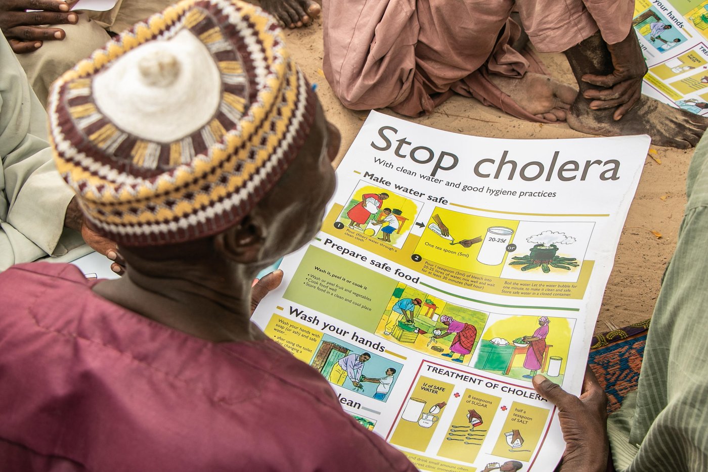 An internally displaced person holds a poster on good hygiene practices.
Photo: Samuel Jegede/NRC