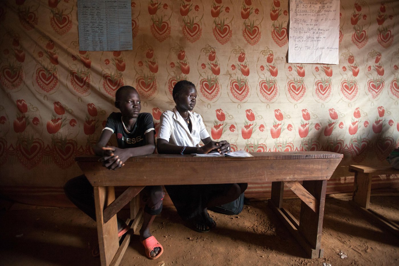 30 November 2016. Juba: (Left to Right) Benjamin Daniel (14 years old) and Nyamandong Isaac (16) are pictured at their school at the UN Protection of Civilians (PoC) site in Juba, South Sudan.
Benjamin is displaced since July 2016 and Nyamandong since the civil war started nearly 3 years ago. The conflict officially broke out on December 15, 2013, between forces loyal to President Salva Kiir and those loyal to former Vice President Riek Machar. Since then, an estimated 1.6 million people has been displaced inside the new country's borders. In addition, more than 640,000 people have fled to neighbouring countries. Hunger is on the rise.
According to OCHA, more than 6.1 million South Sudanese are in need of protection and humanitarian assistance such as food, clean water, education and other basic services.
Nyamandong Isaac Rial's story:
Nyamandong came to the UN Protection of Civilians (PoC) site right after the conflict started in South Sudan, in December 2013. By then, she was in her hometown, in Malakal, with her parents and siblings, 3 brothers and 4 sisters. The father decided to join the rebel forces, but the rest of the family moved to Juba to seek protection at the PoC. “Since then, we don’t know anything about our father,” Nyamandong says, “we can’t communicate with him and we don’t know if he is still alive or not.”
Nyamandong says she is really tired of being displaced. “I don’t see any future here and I just hope peace will come soon,” she explains. She still remembers when she was 16 years old in Malakal, where “I used to enjoy going out freely with my friends.” Now, she admits there is not much to do here. “We can go nowhere,” she adds.
Nyamandong, who wants to become Minister of Education of South Sudan, claims that education is not very suitable in the PoC. “In our school, we don’t have books, pencils…,” she explains. In addition, she regrets that the healthcare is also very limited among the displaced. “We really need more assistance,” she insists.
The young displaced is going to celebrate her third Christmas out of her home. “Nothing is the same here,” Nyamandong explains, “because none of us can buy clothes for the young children and cook especial food for the guests.” But she is not worried about herself. She admits she can manage. But she is more concerned “about the children in the PoC, who don’t understand why they can’t celebrate Christmas properly.”
----------------
Photo by Albert Gonzalez Farran - NRC