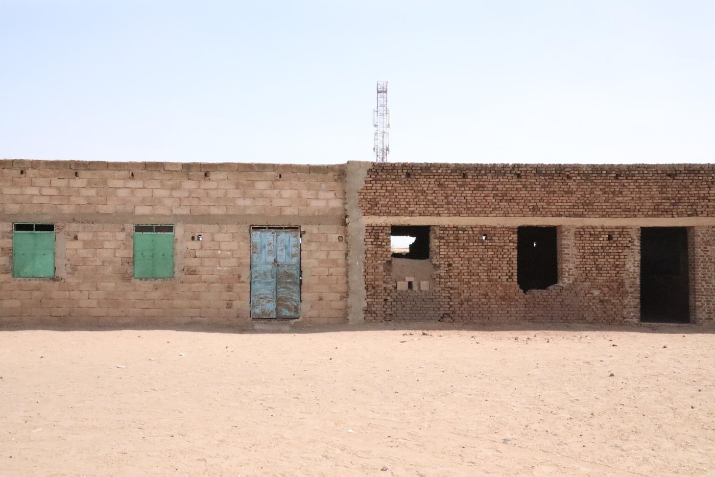 An incomplete wall separates Jwairya School from its neighboring Zaid Ibn Alharith School for boys. Manal remembers how both schools started as just one classroom of hay and mud for both boys and girls.
“Every year, the school administration would collect donations to build one more classroom. After building five classrooms, the Ministry of Education demanded we strictly build classrooms from permanent building material. The locality of Rabak could not afford it, and the school was shut down for a few years,” Manal remembers.
“The school stood empty for years. People had given up to the point they would take the material of the abandoned building and use it for their homes. Children had to cross long roads to get to the schools outside of this area,” Manal she added.
A few years later, parents of the area realized their children were suffering from crossing long distances to get to schools, and the PTA decided to take matters into their own hands. Children were also more motivated to find jobs than to walk the distance to school. The PTA started gathering donations again from families in the area for renovations. Since the funds were limited, people would volunteer to do the construction work. One year at a time, the community built one classroom after the other. And when the school reached eight classrooms, the PTA decided to separate it into two different schools, Jwairya for Girls and Zaid Ibn Alharith for boys.
Like most schools in White Nile, Jwairya School serves a heavily affected displacement area. Families come to places like Al Hila Al Jadeeda seeking shelter from the conflict and floods of South Sudan and the tribal conflict in Darfur. According to UNHCR, Sudan received over 80,000 new South Sudanese refugees, over half of which reside in White Nile. Over 500,000 people were internally displaced by conflict and natural disasters in Sudan in 2021. This is a displacement record, which Sudan has not witnessed since 2014. There are over 600 students in Jwiarya School, of which 9 percent are from internally displaced families and 0.5 percent are from South Sudanese refugee families.
Photo Credit: Rawan Kara/ NRC