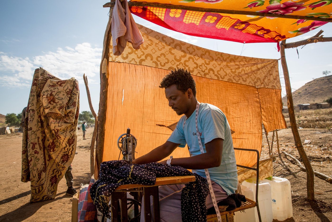 Ebrahim, 24 years old, has set up a small tailor shop in Um Rakuba camp. The only one so far in the camp. Business is good as many refugees had their clothes thorn during the long days of travel. He shares the income with the owner of the sewing machine.
Photo: Ingebjørg Kårstad/NRC