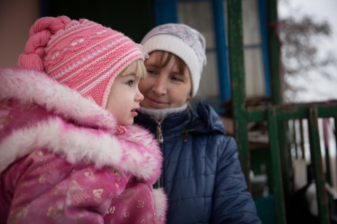 Veronika (4)
Kateryna Matuliz is 29 years old, mother of 3 children, from Popasna town.
“I lived with my husband and two daughters in our own apartment in Popasna. But, four years ago the war came to our town and the constant shelling makes it too risky to stay at home anymore. When the conflict started I was pregnant with my third daughter. One of the shells hit the house of our neighbor and I got so stressed that we immediately had to go to the maternity ward in a town nearby and our daughter Veronika came to this world a little bit earlier”, Kateryna says.
Kateryna and her three daughters moved to her mother’s house in a safer part of the town. The house is very small without basic facilities and can hardly accommodate the big family. Kateryna’s husband left to Russia several years ago to help his sick mother and cannot afford to come to see them often.
“It is impossible to come back home now since the shelling has become even more frequent lately. Every day I have to travel to that district with my children because of school and kindergarten. My daughters also attend dancing and gymnastics there, and we do not want to change our teachers. Every evening we come back to my mother’s home to do homework and to stay overnight. I cannot work, because my youngest daughter gets sick very often”, says Kateryna.
Kateryna’s mother’s house is very old and is located in an open area near the lake where it usually is very windy. To support the family in the winter period, NRC provided them with insulation materials and helped to repair the damaged roof. Kateryna says it has become much warmer than before, and they spend less fuel to heat the house.
Photo: Ingebjørg Kårstad/NRC