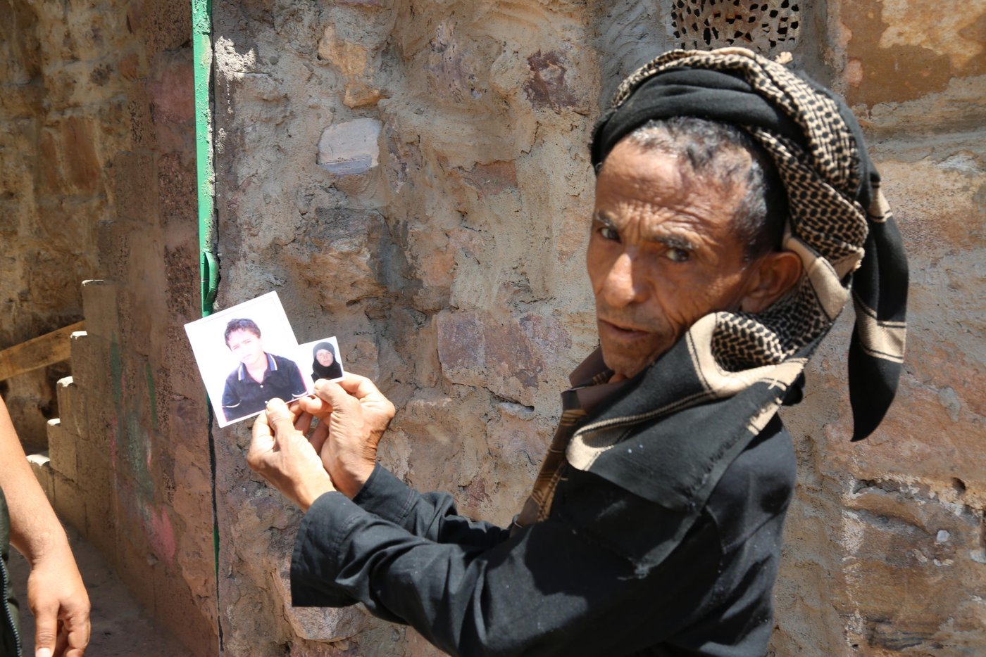 Ghaleb holding photos of his wife and son who were killed by an exploding landmine.