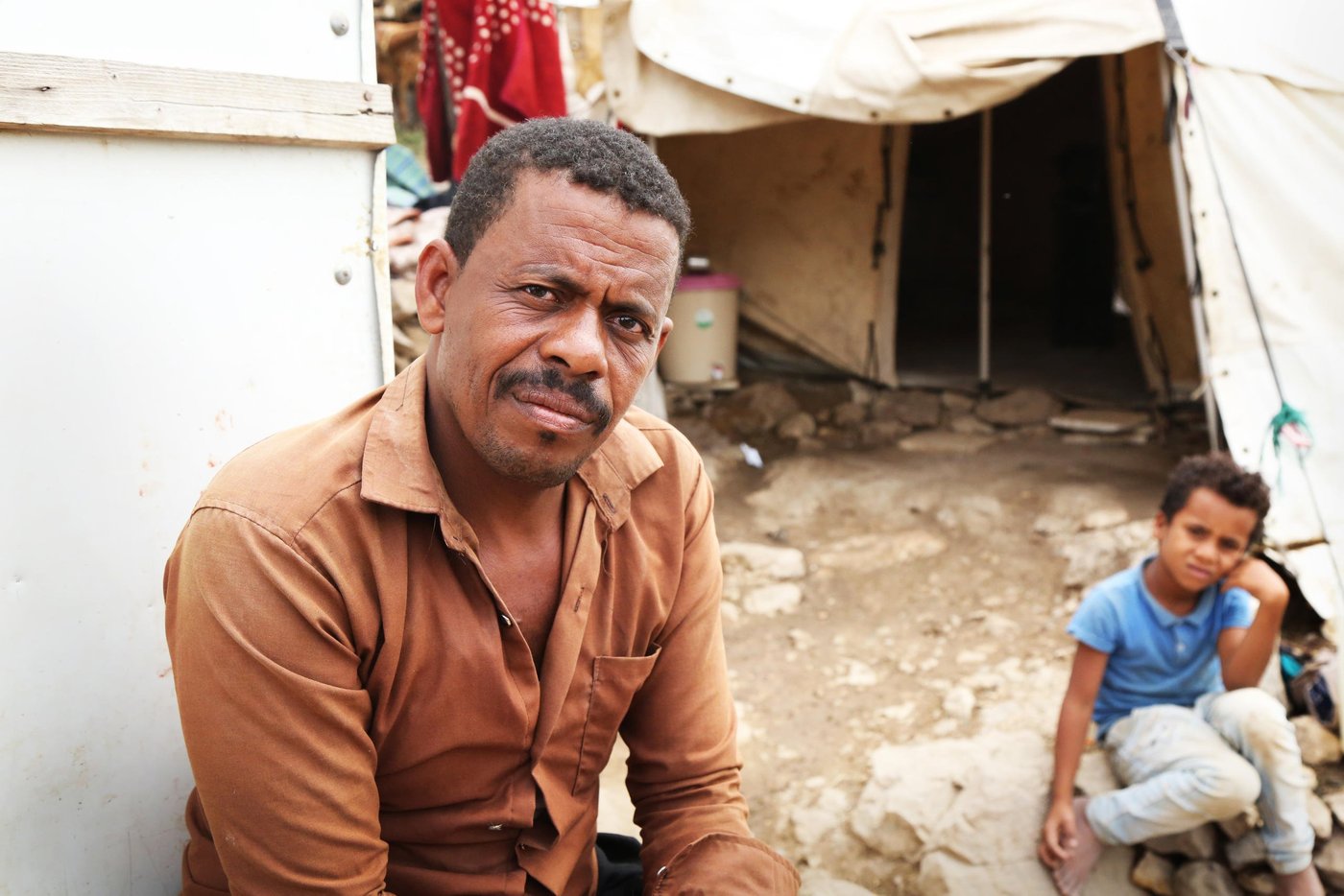 Ahmed Ali Muqbel Ali is a father of eight children. Formerly a stone-breaker, he and his family fled their village in Maqbana district in 2017. Ahmed Ali and his wife and eight children now live in a tent in Al-Malika camp in Taiz. He is jobless, and struggling to provide his family with enough food amid the spread of Covid-19 and an increasing lack of work.

In the last two months, he has seen the cost of flour go up by 40%, and other food prices rising too. “We are more scared of food prices than of corona.”

Ali is doing everything he can to ease the impact on his children, including dividing up one meal into three so they feel like they still are eating three meals. If there isn’t enough food, he gives it to the children and goes hungry himself. “There are times we only eat when necessary. The food for one meal, we divide it into three meals. We used to buy vegetables, fruits and other things but now we can’t. Two weeks ago, we went two days without any food.” 

Photo: Khalid Al-Banna/NRC