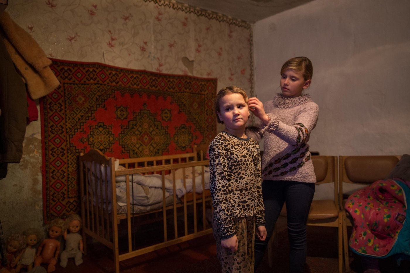 Iryna is 10 years old, and Liliia’s eldest daughter. She still remembers the night their house was hit. Iryna and her sibling all suffer from post-traumatic stress. It is hard to concentrate at school and she has nightmares and anxiety. “The main concern for me now is that the active phase of the war does not break out again. I am afraid that my house will be destroyed again. After all, we hear the sounds of shots every night,”says her mother Liliia. Iryna helps her sister Yana, 7, with her hair.
Background story:
Liliia Poturoieva is 39. She has experienced terrible events that completely changed the life of herself and her large family and left an indelible mark on everyone's soul. She lives in the frontline village of Verkhnia Vilkhova in Stanytsia Luhanska district, Luhansk region.
Liliia has six children. The oldest is Oleksandr. He is 20. He lives separately from his parents and earns his own living. Ihor is 12. He is a shy and calm schoolboy, always ready to help parents with the housework. Her eldest daughter Iryna is 10. She is a schoolgirl and mother's main housekeeper. She cooks and looks after younger children. Yana is 7. She is a first-grade pupil. She is a cheerful, active and very energetic girl. The children are forced to go to school in a neighboring village 5 kilometers away, since there is simply no school in their village.
Her youngest son Illia,5, and daughter Aryna, 2, are always staying at home with their mother. The family cannot afford a kindergarten for children. Now Liliia is pregnant again. This will be the seventh child in the family. Her husband Viktor helps her to cope with all of them.
Before the conflict, the whole big family lived in a small house with two rooms. There was no work. The main income was child allowances and random earnings from the cows, goats, rabbits and poultry.
“There was no work in the village. There was no opportunity to travel to other settlements to work. We tried to make money by selling milk”.
In February 2015, at midnight, heavy shelling began. Viktor, Liliia's husband, went out into the yard to see the direction of the shots. Suddenly a shell fell near their yard, and the second shell landed 7 meters away from Viktor, who was standing on the house porch. Viktor got a serious shell shock and lost his hearing for a while.
The blast wave knocked out all the windows in the house. Under one of the windows there was a child's bed, where Liliia’s youngest son slept. That night Liliia saved the life of her son with her son.
“When the blast hit, I covered my baby with my own body, and the glass from the broken window hit me in the back”.
The consequences of that shelling are still noticeable. Liliia has problems with her speech. She is stuttering. She is not the only one.
“The children experience anxiety, concentration problems, fears and, as a result, urinary incontinence”.
The house was seriously damaged in the blast. All the windows were broken, the front walls were destroyed and the roof and the foundation were seriously damaged. However, Liliia and her family did not dare to leave because it was too risky to leave the house unattended. They tried to repair the house on their own. They covered the broken windows with plastic wrap. They even had to spend their nights in the basement because it was the warmest and the safest place in their household.There was no help from the local authorities.
“At first I didn’t want to ask for help. I did not believe that anyone would really help us. My husband advised me to go to the NRC office and find out about the Heavy repair project, because he heard that NRC had already helped someone in the village”.
Now the house is in the process of restoration. There is a new slate on the roof. Renovation works on the walls have been completed. Three small rooms for the children have been completed. New windows have been installed and internal works are being carried out now.
“The main thing for me now is that the active phase of the war does not break out again. I am afraid that my house will be destroyed again. After all, we hear the sounds of shots every night”, Liliia says.
Photo: Ingebjørg Kårstad/Norwegian Refugee Council