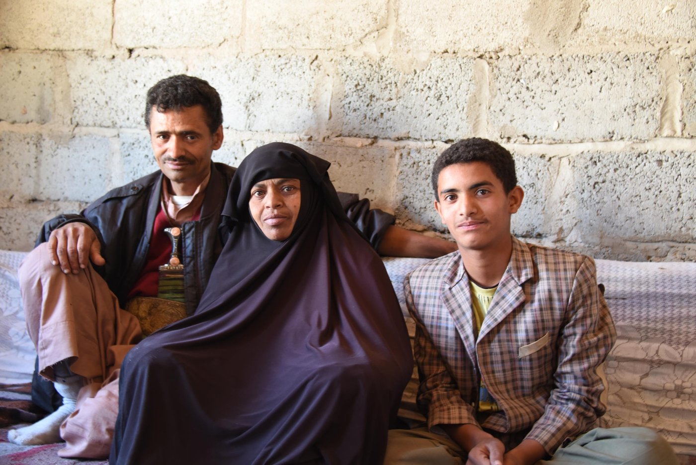 Mahmoud Zeid and his wife Sabah speak fo the day they had to flee their home in July 2015 following an airstrike close to their neighbourhood in Jabal Al Nugm.
Zeid used to work as a tailor but since the war and blockade started he no longer has a job.
Sabah suffers from kidney failure.
They have six children.
NRC provides them with food aid in a project funded by WFP.
Mahmoud said: "Before the war I worked as a tailor. After the war I lost my job. I spent four months without work, work went down drastically, maybe three or four days and then nothing. This is largely because of the electricity situation and the lack of money in people's pockets, there's no movement, it's as if life stopped.
“This is all caused by the war, of course. We have to survive. There is no food, no spending money like there used to be, we get a plate or two of food and get on with it. Even then we don't even have cooking gas.
“I was out of the house with my son Mohammed. We were waiting in the queue for cooking gas, there were some 5,000 cylinders waiting to be refilled. At one point I heard a huge explosion in our neighbourhood, but all of Sana'a was being bombed. I was with Mohammed at the gas distribution point and planes were bombing the area. The planes were bombing everywhere. Then we got missiles raining on us, I don't know what they were, Tomahawks? Scud?
“Here in Nuqm it was hell. The sky above us was covered with debris and shrapnel and smoke. Everything was up in the sky. It was hell.
“My son Mohammad was afraid for his mother. I grabbed him so that we sought cover behind houses. Then we rushed towards home. When we arrived at the foot of the hill to our neighbourhood I let go of our gas cylinder and tried reaching home, but couldn't get through. Everyone was fleeing in a panic, families with children. They fled their houses.
“My wife was very distressed. My daughter Tahani was outside. When I arrived a neighbour told me my daughter was together with his so I told him to take care of her while I went inside. I entered and it was a disaster. It was full of dust and debris. My wife was very tired because of her illness (kidney failure). I gathered them (my wife and children) and we decided to walk towards a school.”
Sabha said: "We went on foot. We took nothing with us, we had not time. During the bombing I was exhausted. I told them let's go to the school. We were too afraid. I felt paralysed till we reached the school. When we reached the school we could hear the missiles. We were a lot of people in one classroom. There were missiles and loud explosions. We were afraid.
“We came back home (after a few months) and we were happy to be back, one rests when he's back home. But I had a lot of cleaning to do. A lot of repairs, so many things were damaged. There was dust and debris all over the place. Everything was scattered on the floor.
Mahmoud said: "Our sewage pipes were destroyed. The windows were gone and we had stones that came in with the blast. This room had a lot of cracks. It was as if the world turned upside down. Our house was damaged by all the blast of the explosions. Our windows were gone, our furniture, the television is gone, the roof has been damaged, all the glass has been broken. We had glass flying from far away into our house.
“I have five daughters and one son. In this situation what kind of future can we talk about? A future for children? It's all bleak. It's a black canvas. This blots out the future of millions of children as regards their health, education, nutrition... nutrition affects growth. These problems brought by the violence affect our children. Children are traumatised by this war, how can we speak of the future? If this conflict goes on it's a future of blood and darkness."
Photo and story collected by Karl Schembri/NRC