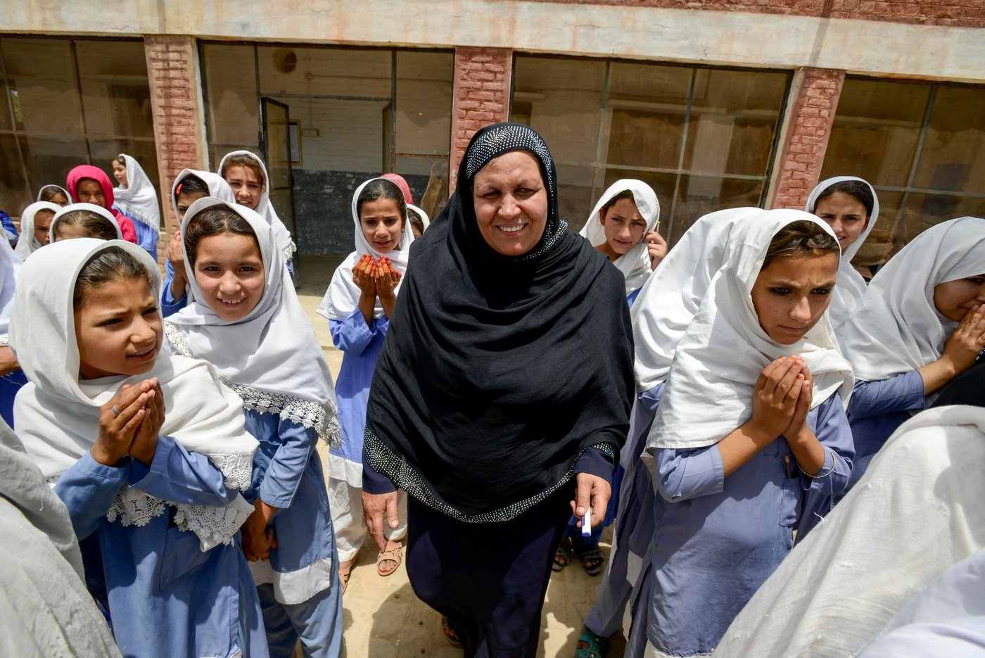 Ms Aqeela Asifi leading the morning assembly at her school in Kot Chandana refugee village in Mianwali, Pakistan, where she teaches Afghan refugee and Pakistani girls.