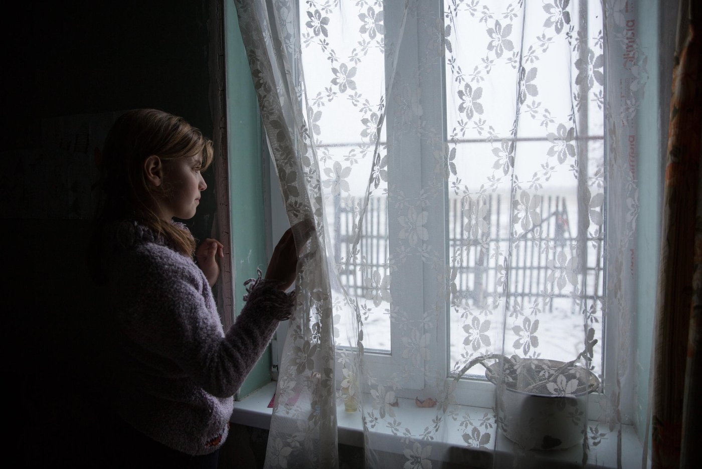 Iryna is 10 years old, and Liliia’s eldest daughter. She still remembers the night their house was hit. Iryna and her sibling all suffer from post-traumatic stress. It is hard to concentrate at school and she has nightmares and anxiety. “The main concern for me now is that the active phase of the war does not break out again. I am afraid that my house will be destroyed again. After all, we hear the sounds of shots every night,”says her mother Liliia. 

Background story:
Liliia Poturoieva is 39. She has experienced terrible events that completely changed the life of herself and her large family and left an indelible mark on everyone's soul. She lives in the frontline village of Verkhnia Vilkhova in Stanytsia Luhanska district, Luhansk region. 

Liliia has six children. The oldest is Oleksandr. He is 20. He lives separately from his parents and earns his own living. Ihor is 12. He is a shy and calm schoolboy, always ready to help parents with the housework. Her eldest daughter Iryna is 10. She is a schoolgirl and mother's main housekeeper. She cooks and looks after younger children. Yana is 7. She is a first-grade pupil. She is a cheerful, active and very energetic girl. The children are forced to go to school in a neighboring village 5 kilometers away, since there is simply no school in their village.

Her youngest son Illia,5, and daughter Aryna, 2, are always staying at home with their mother. The family cannot afford a kindergarten for children. Now Liliia is pregnant again. This will be the seventh child in the family. Her husband Viktor helps her to cope with all of them.

Before the conflict, the whole big family lived in a small house with two rooms. There was no work. The main income was child allowances and random earnings from the cows, goats, rabbits and poultry. 

“There was no work in the village. There was no opportunity to travel to other settlements to work. We tried to make money by selling milk”.

In February 2015, at midnight, heavy shelling began. Viktor, Liliia's husband, went out into the yard to see the direction of the shots. Suddenly a shell fell near their yard, and the second shell landed 7 meters away from Viktor, who was standing on the house porch. Viktor got a serious shell shock and lost his hearing for a while. 
The blast wave knocked out all the windows in the house. Under one of the windows there was a child's bed, where Liliia’s  youngest son slept. That night Liliia saved the life of her son with her son. 

“When the blast hit, I covered my baby with my own body, and the glass from the broken window hit me in the back”.

The consequences of that shelling are still noticeable. Liliia has problems with her speech. She is stuttering. She is not the only one.

“The children experience anxiety, concentration problems, fears and, as a result, urinary incontinence”.

The house was seriously damaged in the blast. All the windows were broken, the front walls were destroyed and the roof and the foundation were seriously damaged. However, Liliia and her family did not dare to leave because it was too risky to leave the house unattended. They tried to repair the house on their own. They covered the broken windows with plastic wrap. They even had to spend their nights in the basement because it was the warmest and the safest place in their household.There was no help from the local authorities. 

“At first I didn’t want to ask for help. I did not believe that anyone would really help us. My husband advised me to go to the NRC office and find out about the Heavy repair project, because he heard that NRC had already helped someone in the village”.

Now the house is in the process of restoration. There is a new slate on the roof. Renovation works on the walls have been completed. Three small rooms for the children have been completed. New windows have been installed and internal works are being carried out now.

 “The main thing for me now is that the active phase of the war does not break out again. I am afraid that my house will be destroyed again. After all, we hear the sounds of shots every night”, Liliia says. 

Photo: Ingebjørg Kårstad/Norwegian Refugee Council