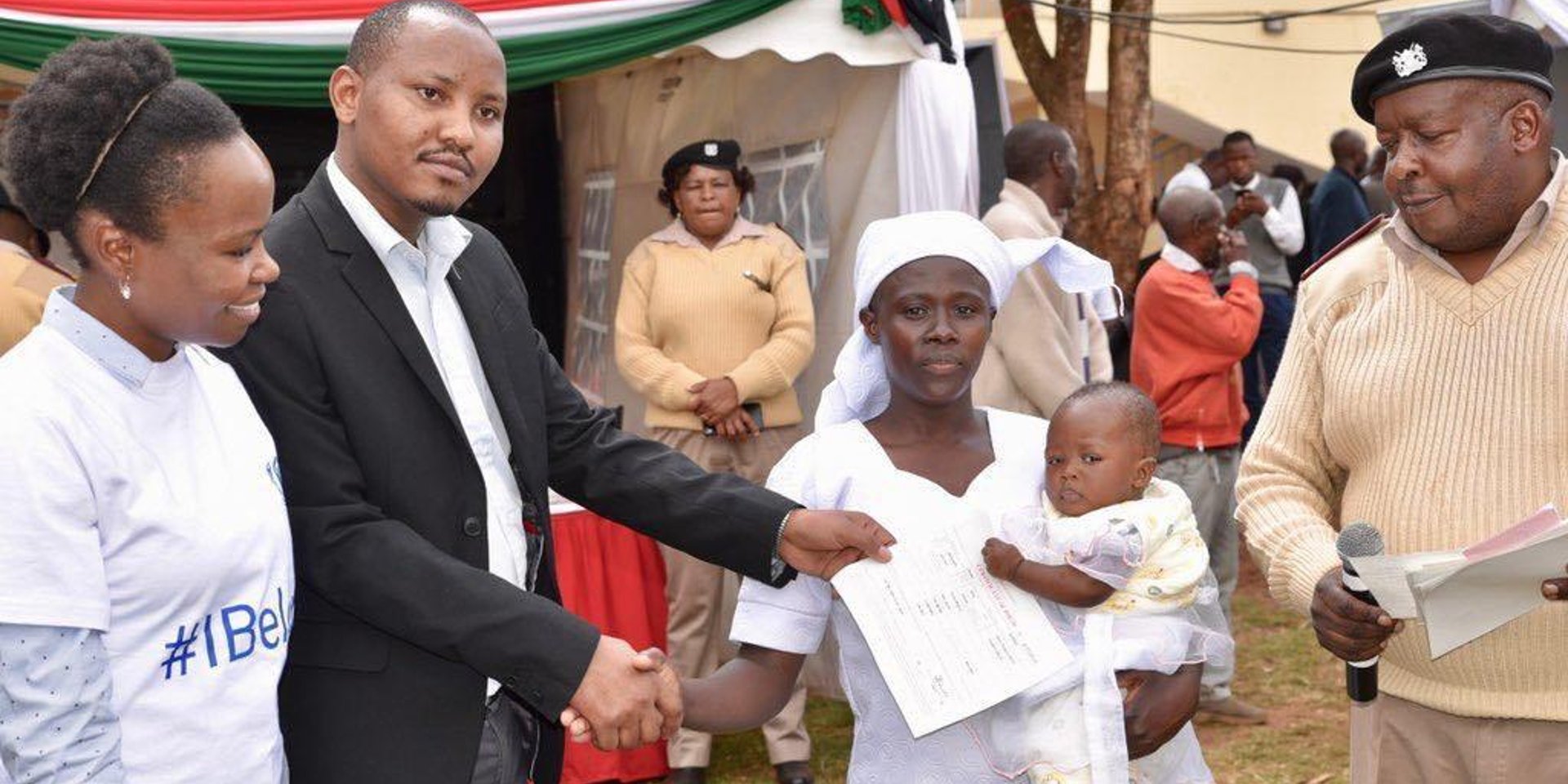 Women shakes hand man presenter her a birth certificate for her baby at a mobile birth registration exercise.
