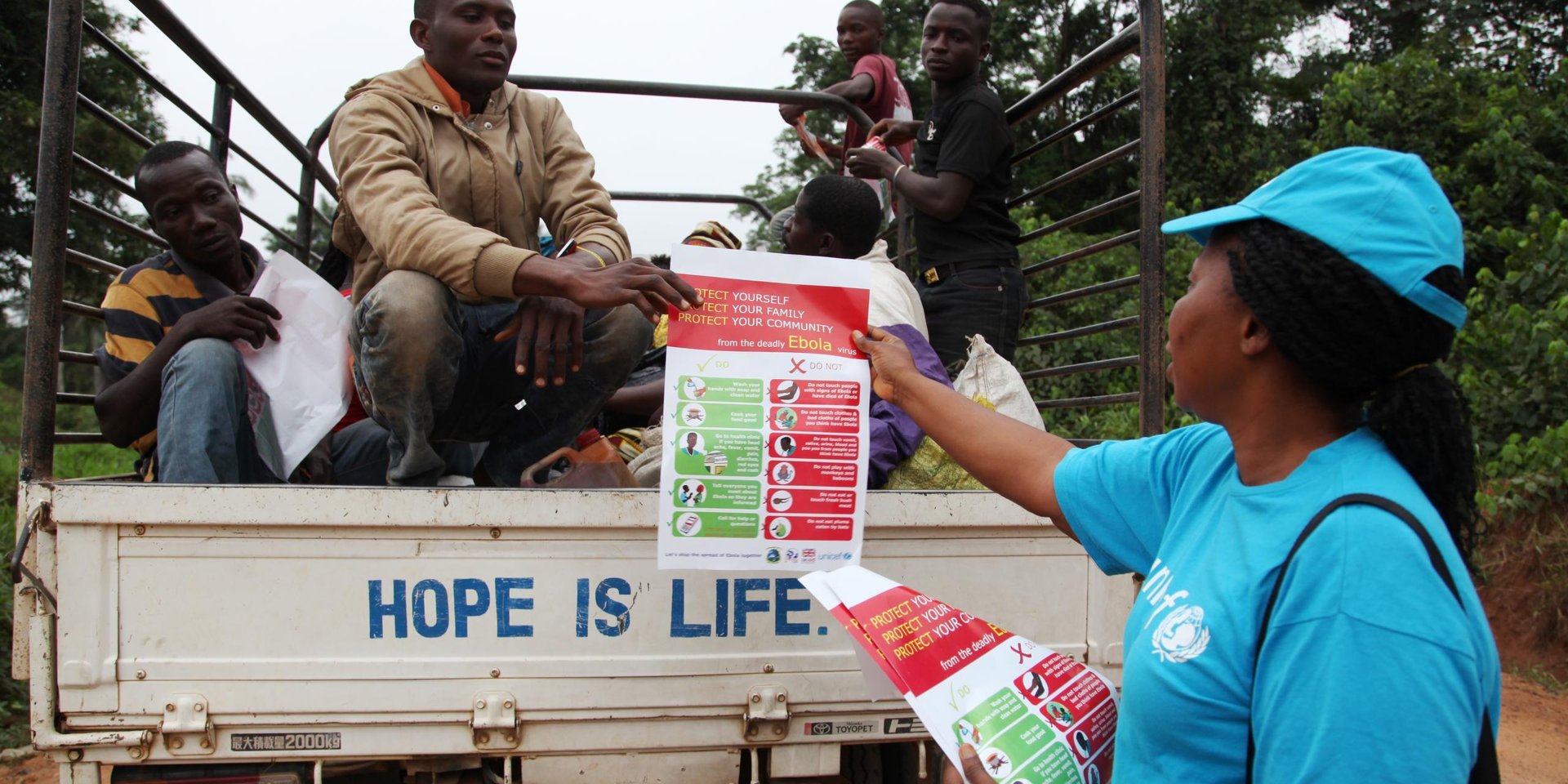 In April 2014 in Liberia, a UNICEF worker in the city of Voinjama, in Lofa County, distributes posters bearing information on the symptoms of Ebola virus disease and best practices to help prevent its spread. (Photo: NORCAP)