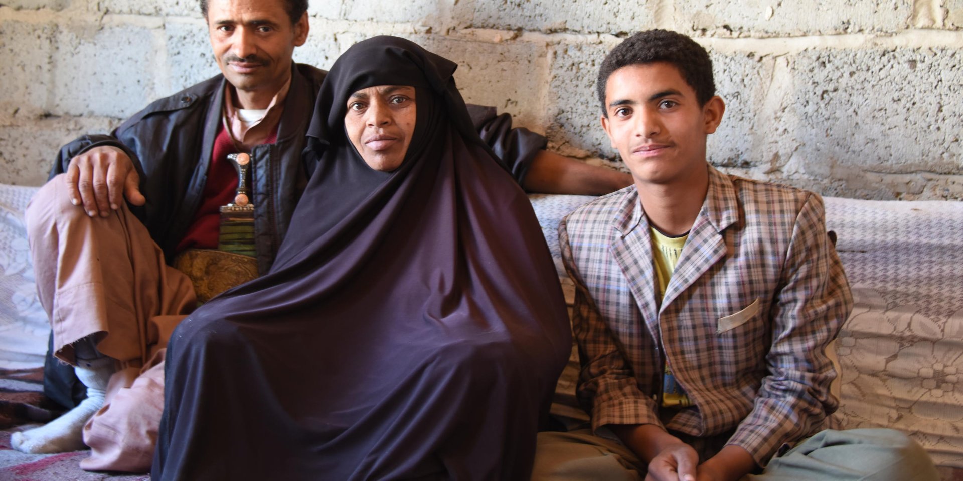 Mahmoud Zeid and his wife Sabah speak fo the day they had to flee their home in July 2015 following an airstrike close to their neighbourhood in Jabal Al Nugm.
Zeid used to work as a tailor but since the war and blockade started he no longer has a job.
Sabah suffers from kidney failure.
They have six children.
NRC provides them with food aid in a project funded by WFP.

Mahmoud said: "Before the war I worked as a tailor. After the war I lost my job. I spent four months without work, work went down drastically, maybe three or four days and then nothing. This is largely because of the electricity situation and the lack of money in people's pockets, there's no movement, it's as if life stopped.

“This is all caused by the war, of course. We have to survive. There is no food, no spending money like there used to be, we get a plate or two of food and get on with it. Even then we don't even have cooking gas.

“I was out of the house with my son Mohammed. We were waiting in the queue for cooking gas, there were some 5,000 cylinders waiting to be refilled. At one point I heard a huge explosion in our neighbourhood, but all of Sana'a was being bombed. I was with Mohammed at the gas distribution point and planes were bombing the area. The planes were bombing everywhere. Then we got missiles raining on us, I don't know what they were, Tomahawks? Scud? 

“Here in Nuqm it was hell. The sky above us was covered with debris and shrapnel and smoke. Everything was up in the sky. It was hell.

“My son Mohammad was afraid for his mother. I grabbed him so that we sought cover behind houses. Then we rushed towards home. When we arrived at the foot of the hill to our neighbourhood I let go of our gas cylinder and tried reaching home, but couldn't get through. Everyone was fleeing in a panic, families with children. They fled their houses.

“My wife was very distressed. My daughter Tahani was outside. When I arrived a neighbour told me my daughter was together with his so I told him to take care of her while I went inside. I entered and it was a disaster. It was full of dust and debris. My wife was very tired because of her illness (kidney failure). I gathered them (my wife and children) and we decided to walk towards a school.”

Sabha said: "We went on foot. We took nothing with us, we had not time. During the bombing I was exhausted. I told them let's go to the school. We were too afraid. I felt paralysed till we reached the school. When we reached the school we could hear the missiles. We were a lot of people in one classroom. There were missiles and loud explosions. We were afraid.

“We came back home (after a few months) and we were happy to be back, one rests when he's back home. But I had a lot of cleaning to do. A lot of repairs, so many things were damaged. There was dust and debris all over the place. Everything was scattered on the floor.

Mahmoud said: "Our sewage pipes were destroyed. The windows were gone and we had stones that came in with the blast. This room had a lot of cracks. It was as if the world turned upside down. Our house was damaged by all the blast of the explosions. Our windows were gone, our furniture, the television is gone, the roof has been damaged, all the glass has been broken. We had glass flying from far away into our house.

“I have five daughters and one son. In this situation what kind of future can we talk about? A future for children? It's all bleak. It's a black canvas. This blots out the future of millions of children as regards their health, education, nutrition... nutrition affects growth. These problems brought by the violence affect our children. Children are traumatised by this war, how can we speak of the future? If this conflict goes on it's a future of blood and darkness."

Photo and story collected by Karl Schembri/NRC