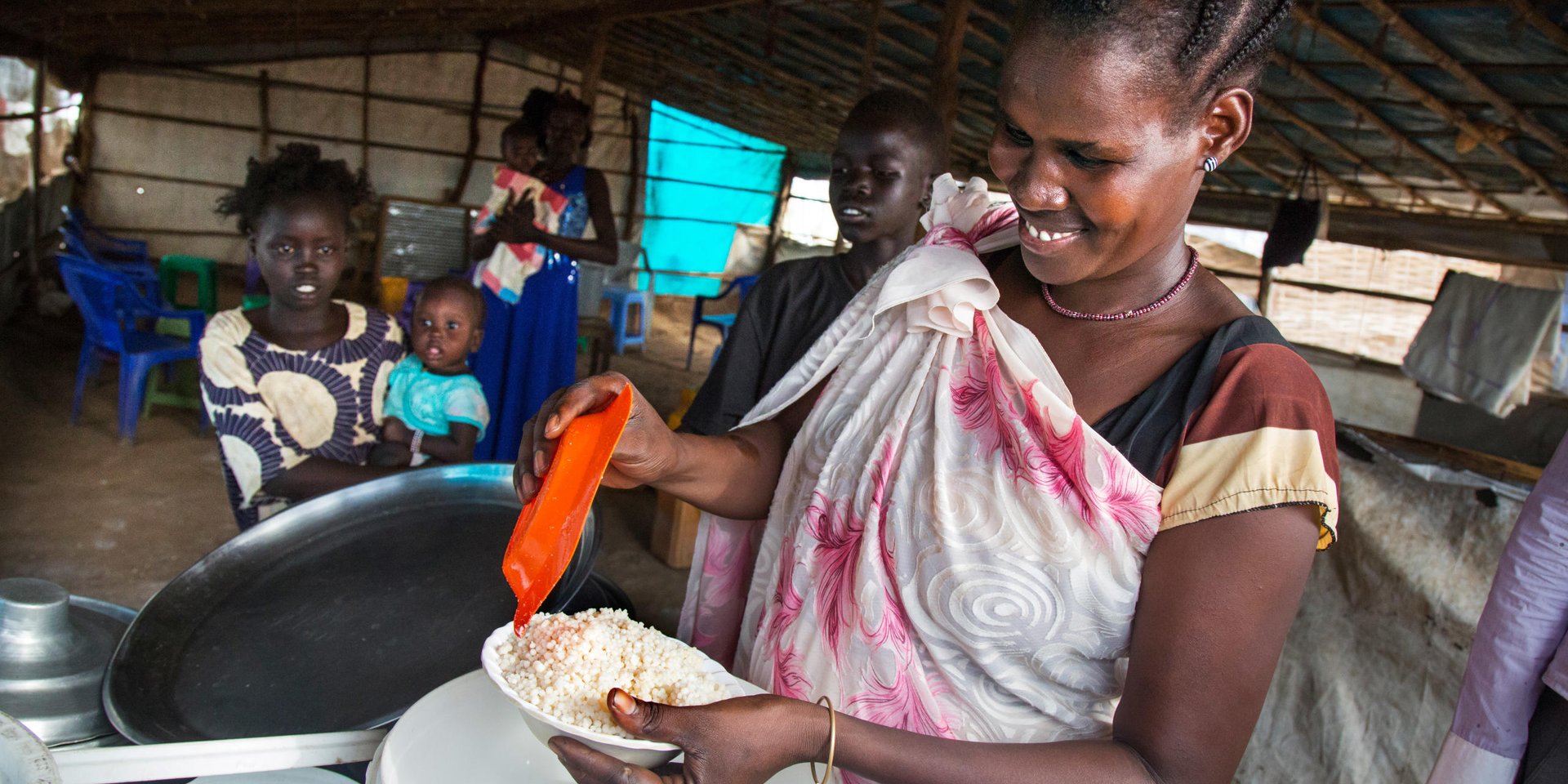 30 November 2016. Juba: (Right) Nyakuan Dador, originally from Mangatein, prepares food at her shelter of the UN Protection of Civilians (PoC) site in Juba, South Sudan.

Nyakuan, mother of six children, doesn't know the whereabouts of her husband who is a member of the opposition forces. She has been displaced with her children since the civil war started nearly 3 years ago. The conflict officially broke out on December 15, 2013, between forces loyal to President Salva Kiir and those loyal to former Vice President Riek Machar. Since then, an estimated 1.6 million people has been displaced inside the new country's borders. In addition, more than 640,000 people have fled to neighbouring countries. Hunger is on the rise.

According to OCHA, more than 6.1 million South Sudanese are in need of protection and humanitarian assistance such as food, clean water, education and other basic services.

Nyakuan Dador's story:

Nyakuan moved to the PoC right after the conflict started in December 2013. Her husband goes regularly in and out of the IDP camp to work as a trader in different villages to help the family to move on. “But it’s really hard to sustain our big family with so little income,” she explains. That’s why she also runs a small restaurant at the PoC.

Nyakuan complains about the lack of good education and healthcare, and even food. “Life was very different before the war,” the woman remembers, “in our homeland we used to have money to pay the hospital and school fees.” The mother regrets they are totally under the assistance of the humanitarian organizations. “These organizations are our parents now,” she says.

Nyakuan is a real supporter of good education in the PoC. “If our children go to the school everyday, they will become something good in the future,” she believes. However, Nyakuan admits that teachers are not paid and school materials are very short. That’s why her only message to the international community is providing support on education for the new generations.

“It has been a long time since we celebrated a proper Christmas,” Nyakuan says. She would like to cook something special for her guests, “but now there is nothing to prepare and no guests to come to my shelter.”

----------------

Photo by Albert Gonzalez Farran - NRC