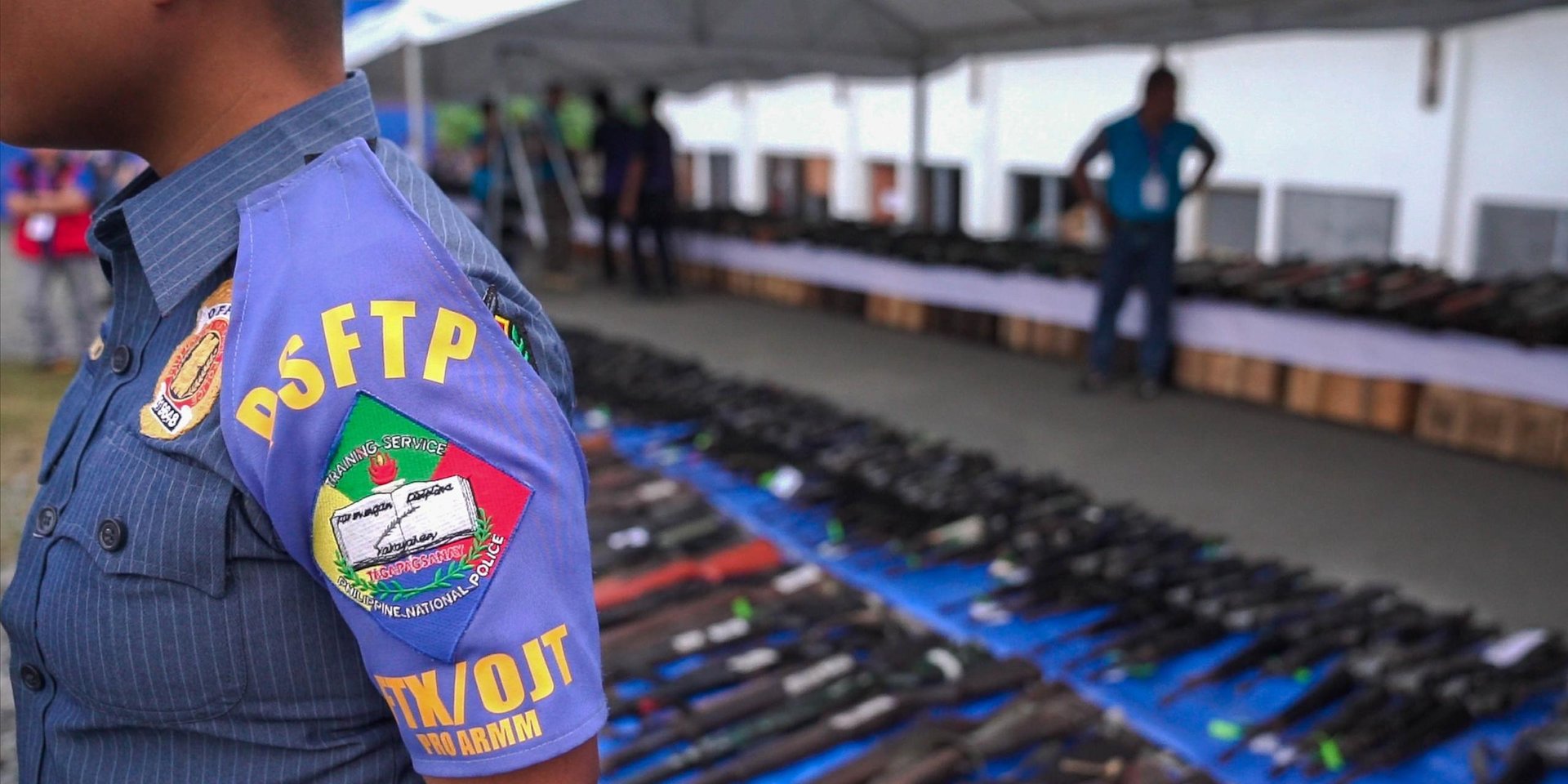 Officer stands in front of a decommissioned weapons.