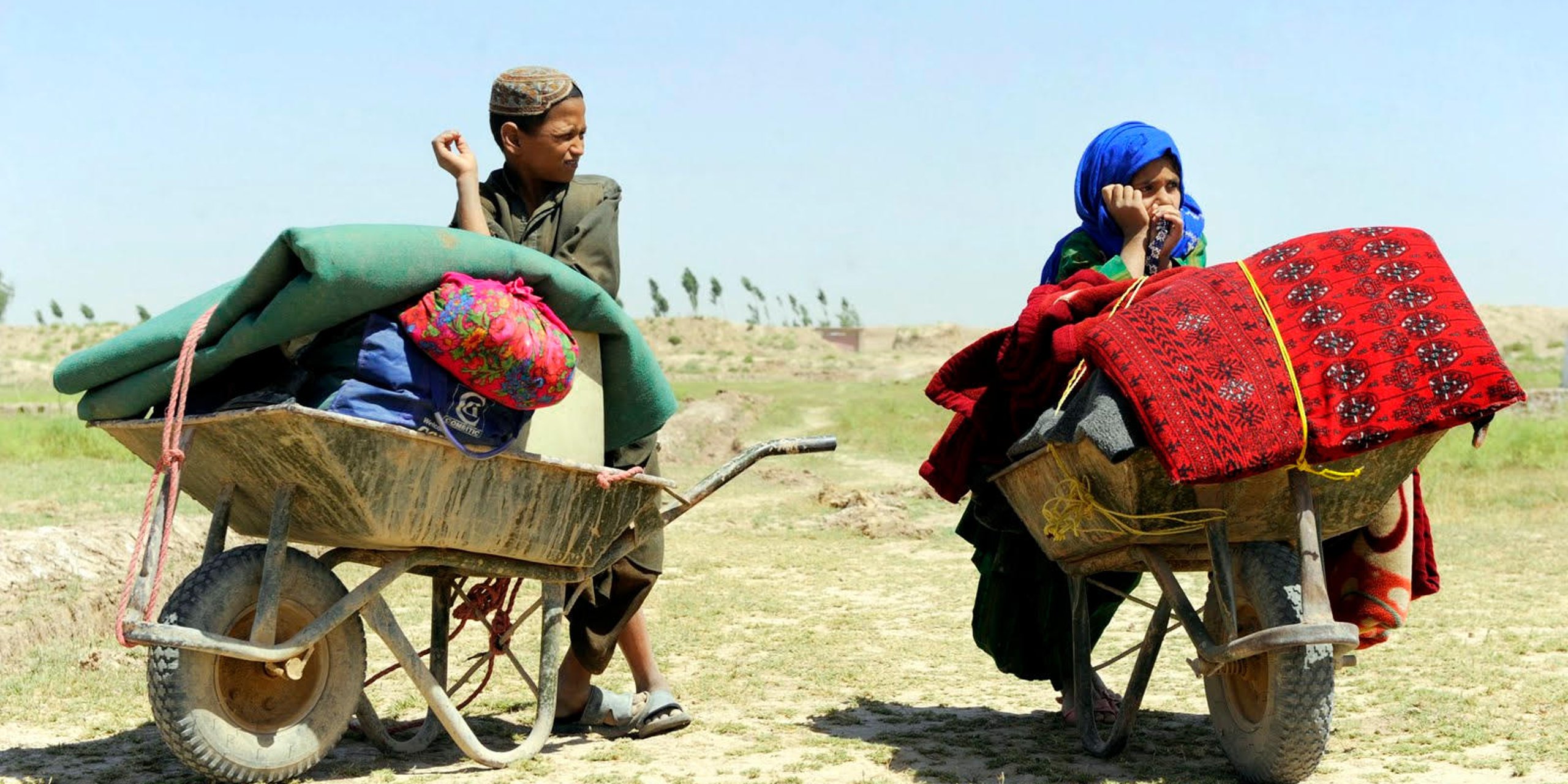 9 year old Marhaba and her cousin, 13 year old Gul Agha, take a break while carrying family belongings to a relative’s tent in an IDP settlement in Herat. Province, June 5, 2012. Photo Credit: NRC/Farzana Wahidy