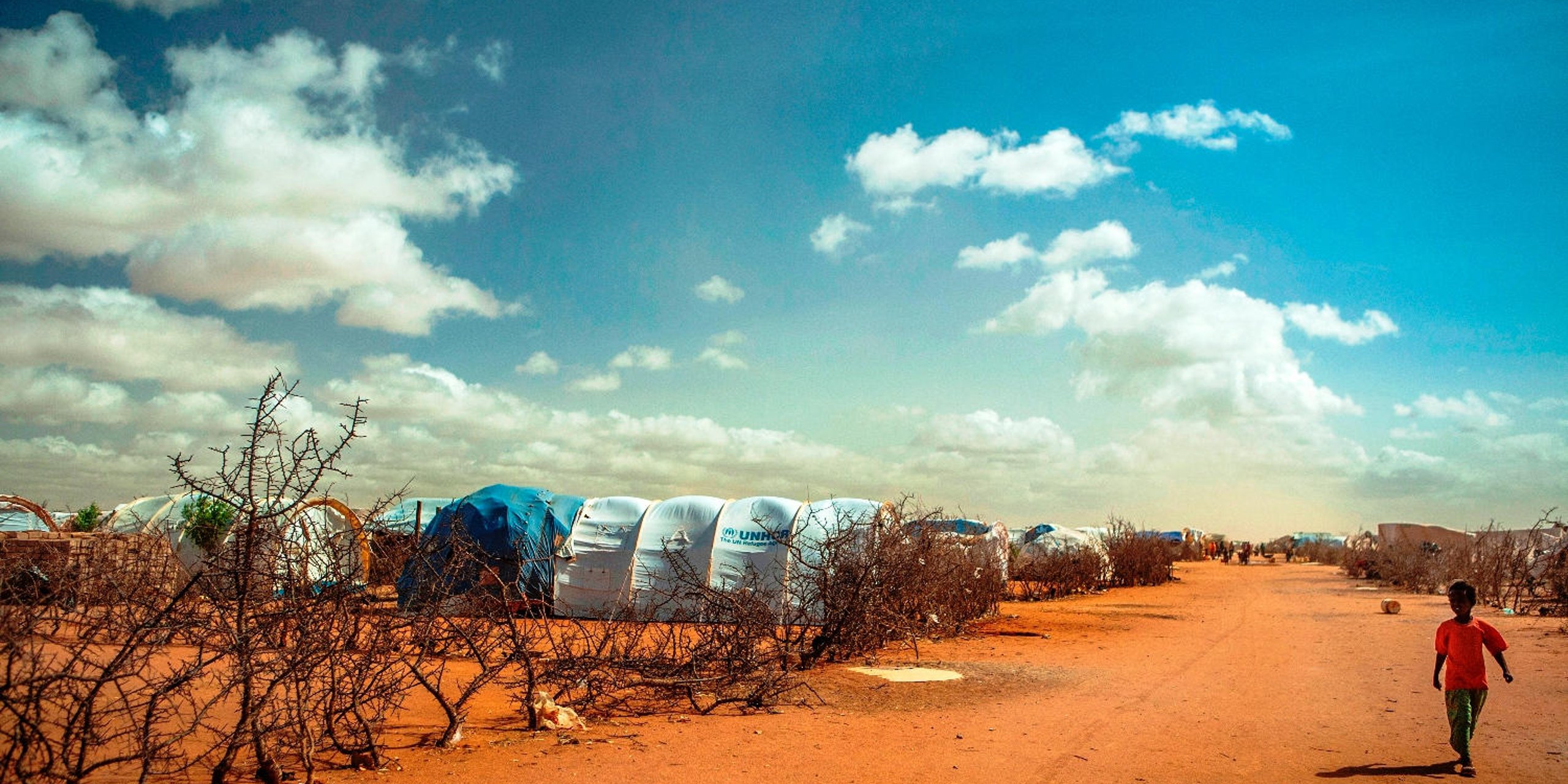 The Dadaab camps (Ifo, Dagahaley, Hagadera) were constructed in the early 1990s. Ifo camp was first settled by refugees from the civil war in Somalia and later efforts were made by UNHCR to improve the camp. In 2006, flooding severely affected the region. More than 2,000 homes in the Ifo refugee camp were destroyed, forcing the relocation of more than 10,000 refugees. Here a boy walks between two 'blocks' in Ifo camp of Dadaab, the world’s largest refugee camp with 464,000 registered refugees, 115,000 of which arrived in 2011 from southern Somalia due to conflict and drought. 29May12.