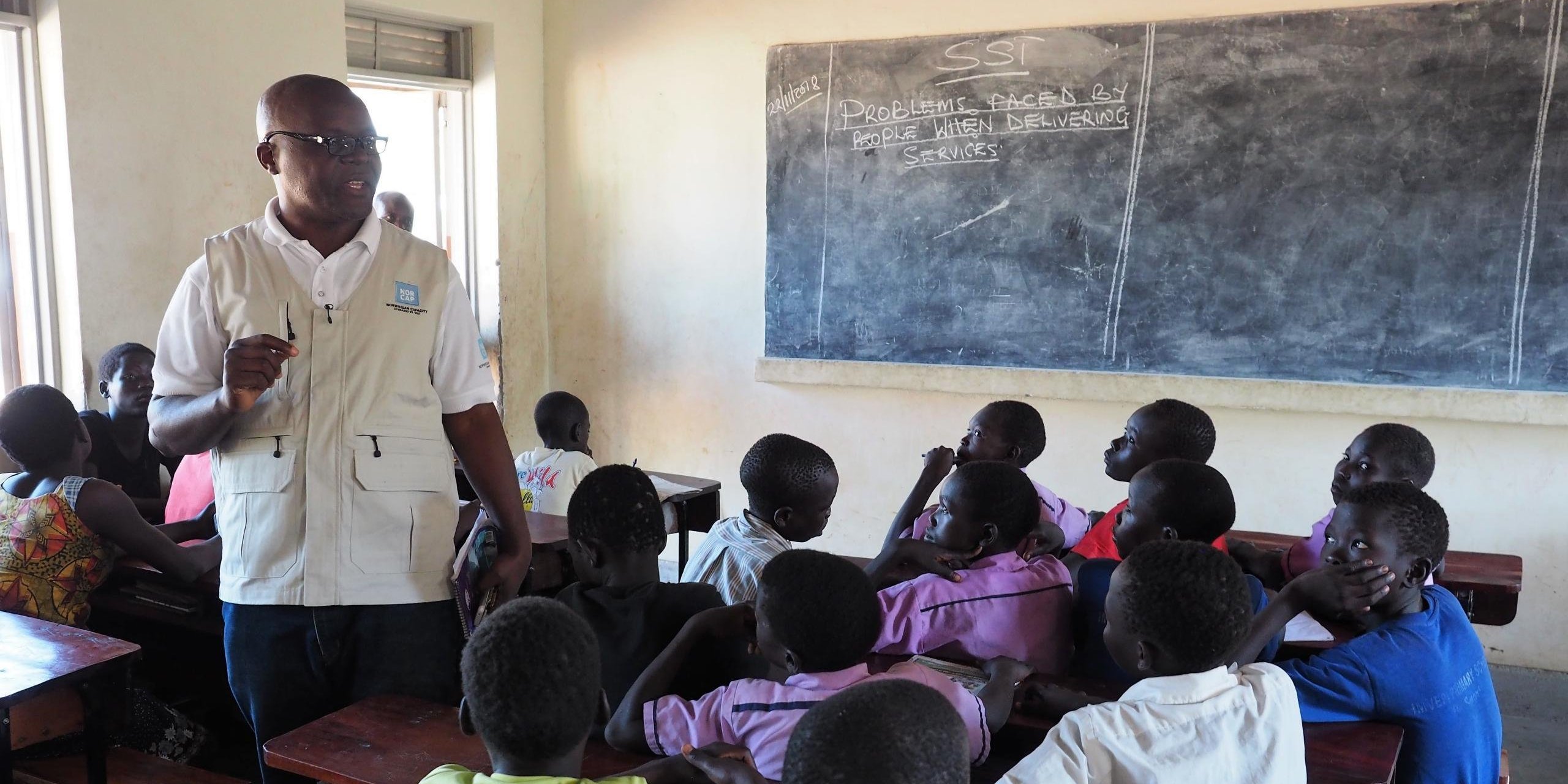 Education in emergencies expert Emile Ntampera talking to students in a school where South Sudanese refugee children learn together with Ugandan children. Imvepi refugee settlement. (Photo: NORCAP/Ida Sem Fossvik)