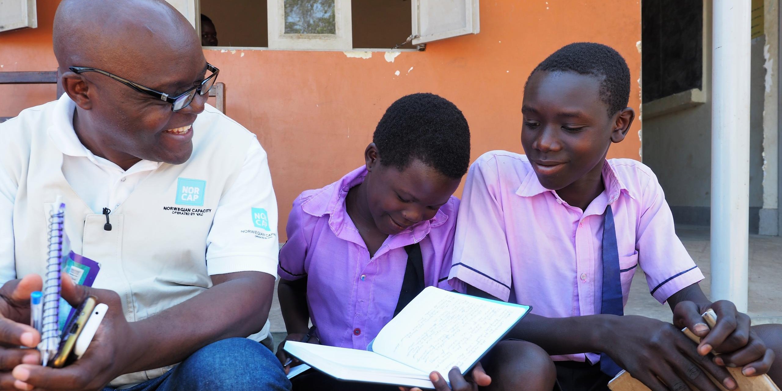 Education in emergencies expert, Emile Ntampera with Ugandan school children, Ajiko Emmacuiel (13) and Lemaku Christopher (14). (Photo: NORCAP/Ida Sem Fossvik)
