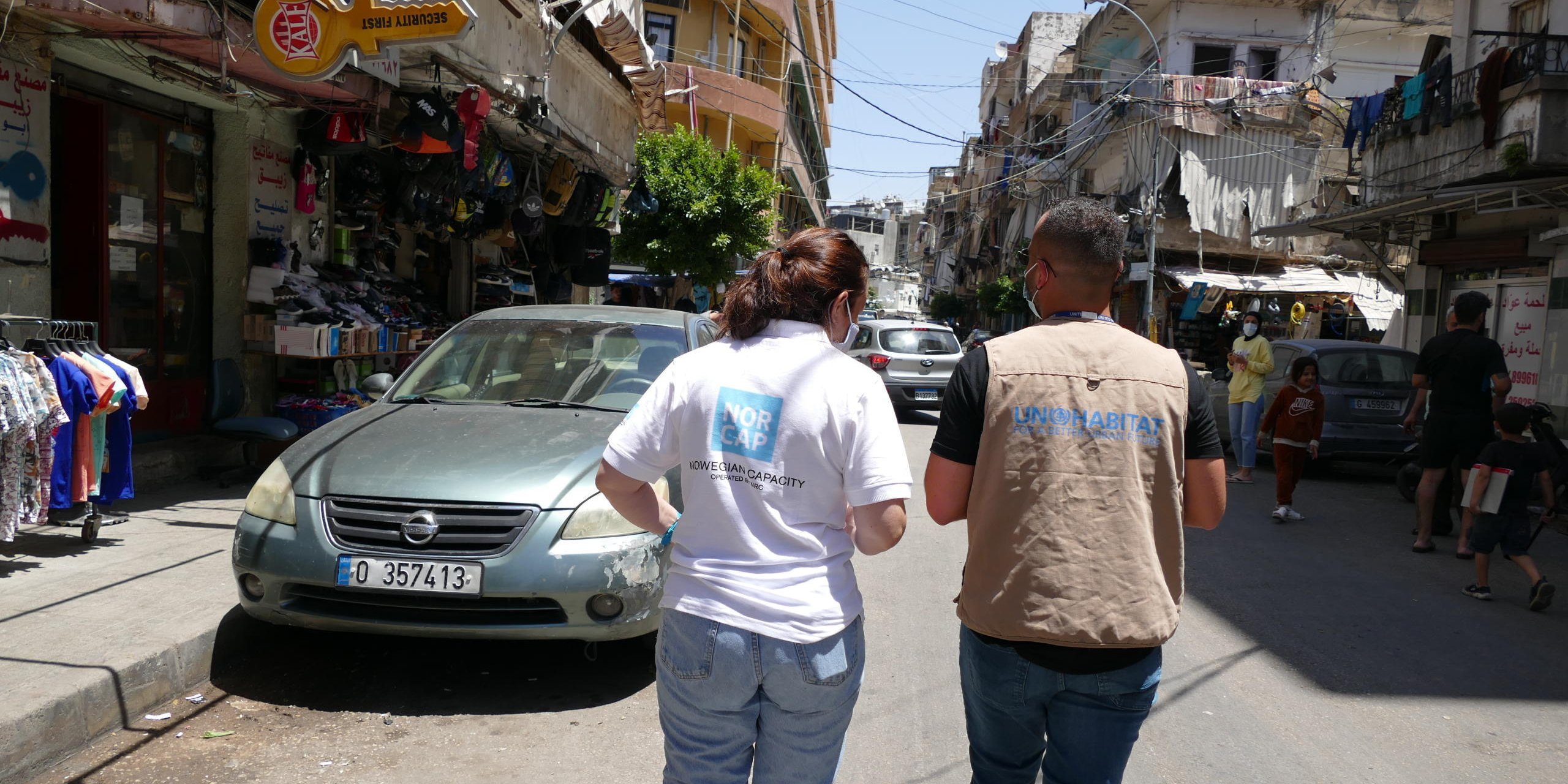 A woman and a man walking down a busy Beirut city street, with their backs to the camera.