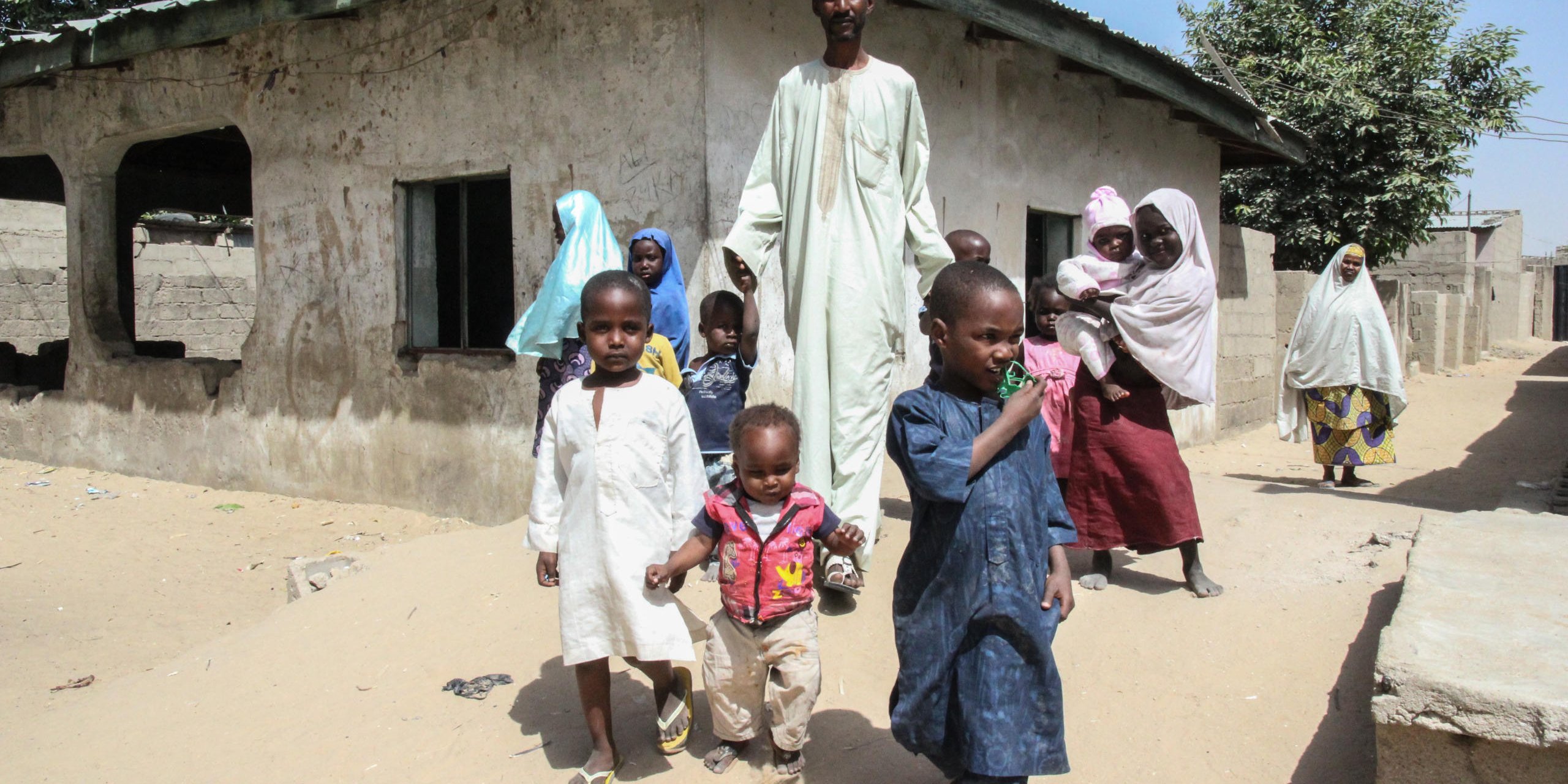 Mustapha with some of the children of the five displaced families he is hosting in his home in Galtimari.
Many displaced people fled their homes in search of safety, leaving behind all they had. Some of them came to Galtimari area of Maiduguri where many kind hearted people have opened their homes and have accepted displaced families to live with them.
Mustapha is 42 year old businessman from Jere local government area. He has 2 wives and 11 children. He owns a large compound with some unfinished structures which he opened up to host 5 displaced families which includes 2 male headed households and 3 widows. The 5 families have a total of 36 children.
When the displaced families came into the community, they initially lived in the community leader’s house which then became very congested. Mustapha offered to assist the situation and invited some of the families to live in his compound. At that time, he did not know any of them but this did not stop him from assisting them. He empathised with their situation and felt an obligation to support them.
In the beginning it wasn’t easy for Mustapha and his family to get along with the visitors but as time passed, the strangers became part of his bigger family. The families need food, livelihood options and education for their children. Their current houses are still congested and there is need for more homes to accommodate them. Mustapha wishes that peace would be restored in the state so that these people can safely return to their homes and continue with their lives.
One of the widows living with Mustapha is Yagana who came from Jere Larea. She is 35 years old and has 7 children. Back home, she was a tailor and a farmer. Her husband died 5 years ago.
Yagana vividly remembers how her town was invaded by insurgents and they heard the loud sounds of explosions and gunshots that killed many people. Her family together with many others left behind everything and fled for safety. It took them 3 days of walking through bushes before they got a vehicle to transport them to Maiduguri
According to Yagana, Mustapha joyfully offered to provide them with accommodation and they are happy staying with him. She is however saddened by the fact that she cannot go back home, they have inadequate food, her children are no longer going to school and she has limited means to fend for her family. She wishes that peace is soon restored in her village so that she and her family can go back and resume their lives.
Some of Mustapha quotes:
“When they came they had no place to sleep, no place to stay. I met them sitting with their children without food and a place to sleep”
“The way it hurt me is that these people had houses, they were living on their own”
“I felt bad at that time because if something like this happens, I am not above it, then I said if you help someone today tomorrow someone will help you”
“they were living a good life they had their town before Allah allowed it that crisis made them to flee here”
Now I wish they will have a peaceful living, get education and go back to their village and get a peaceful living just like us
Some of Yagana quotes:
“When we heard sound of bomb blast, they killed so many people that is why we fled and left the town, they came and killed people”
“We came to this house, this man he received us joyfully then we came in and stayed in his house”
It’s because it’s not safe, if it was safe, we would have gone back
My wish in the future is that I want if it’s safe, we will go back to our homes and stay with our children
We need our children to go to school, we need food stuff, we need something to do to generate income, household utensils, all these, we don’t have
Photo: NRC/Ingrid Prestetun